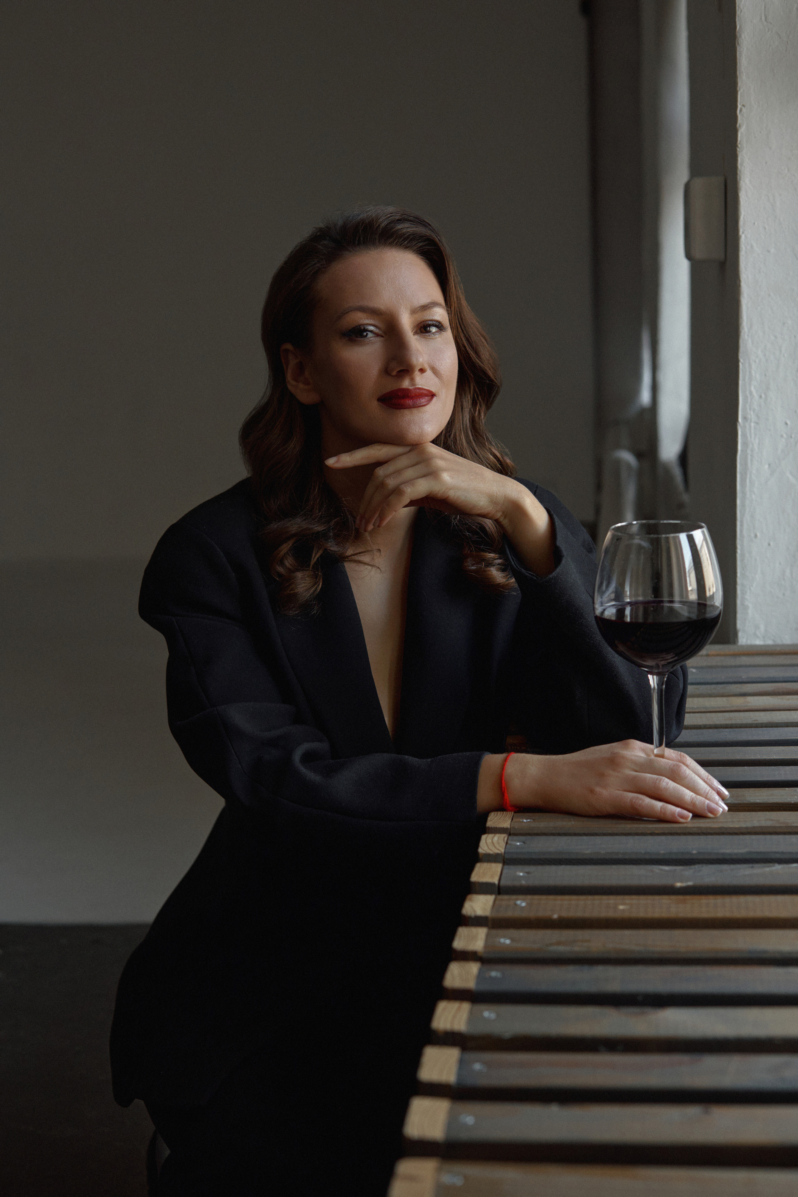 Женский портрет с бокалом вина у окна в темном ключе