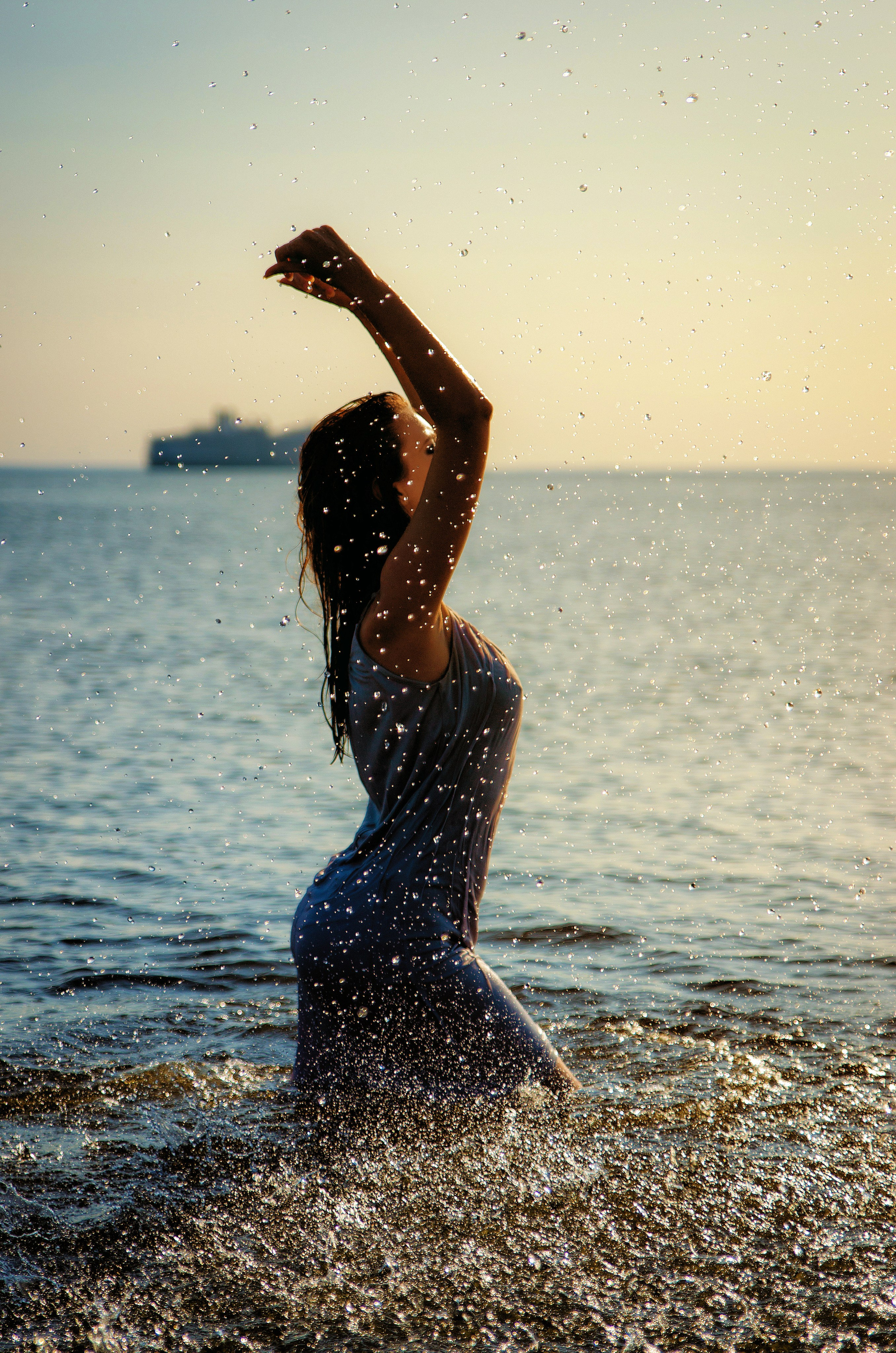 девушка с красивой фигурой брызгает воду, подняв руки, фотосессия на финском заливе