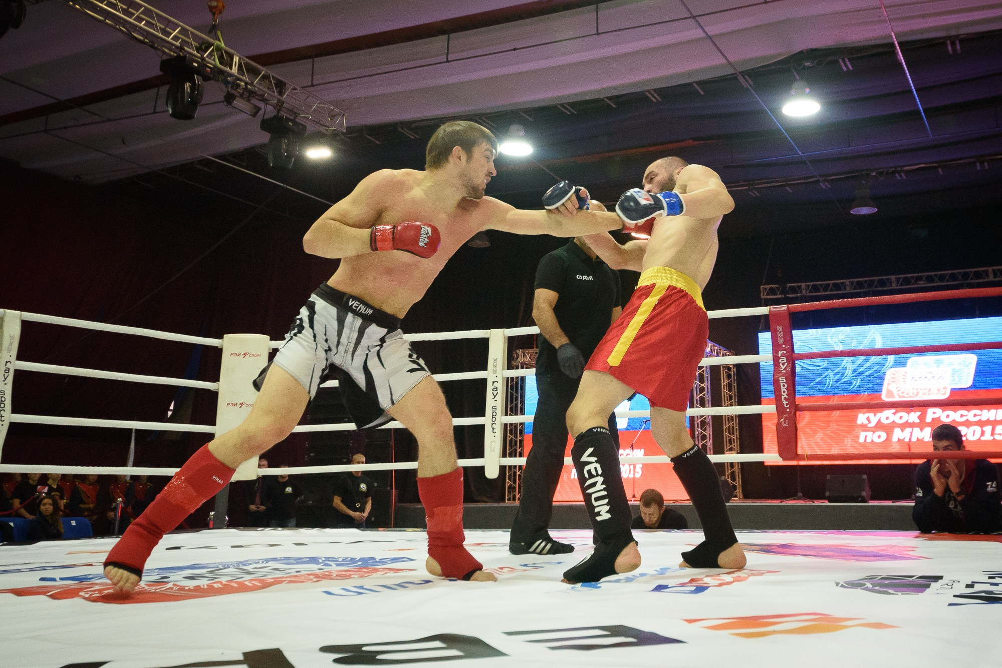 Спортсмен в красных перчатках наносит удар спортсмену в черных перчатках