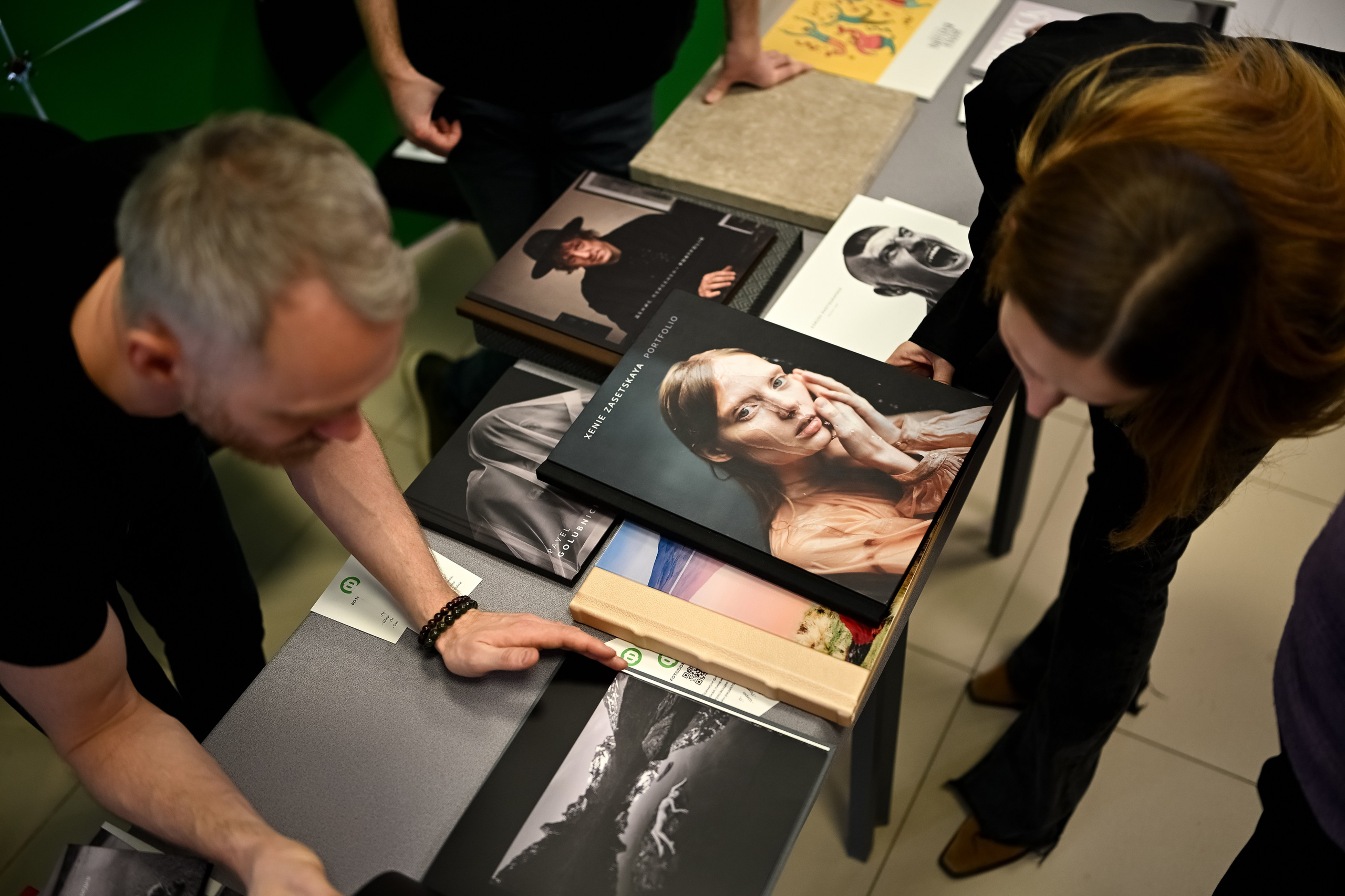 Гости фестиваля рассматривают фотокниги и печатные портфолио в зоне партнёров