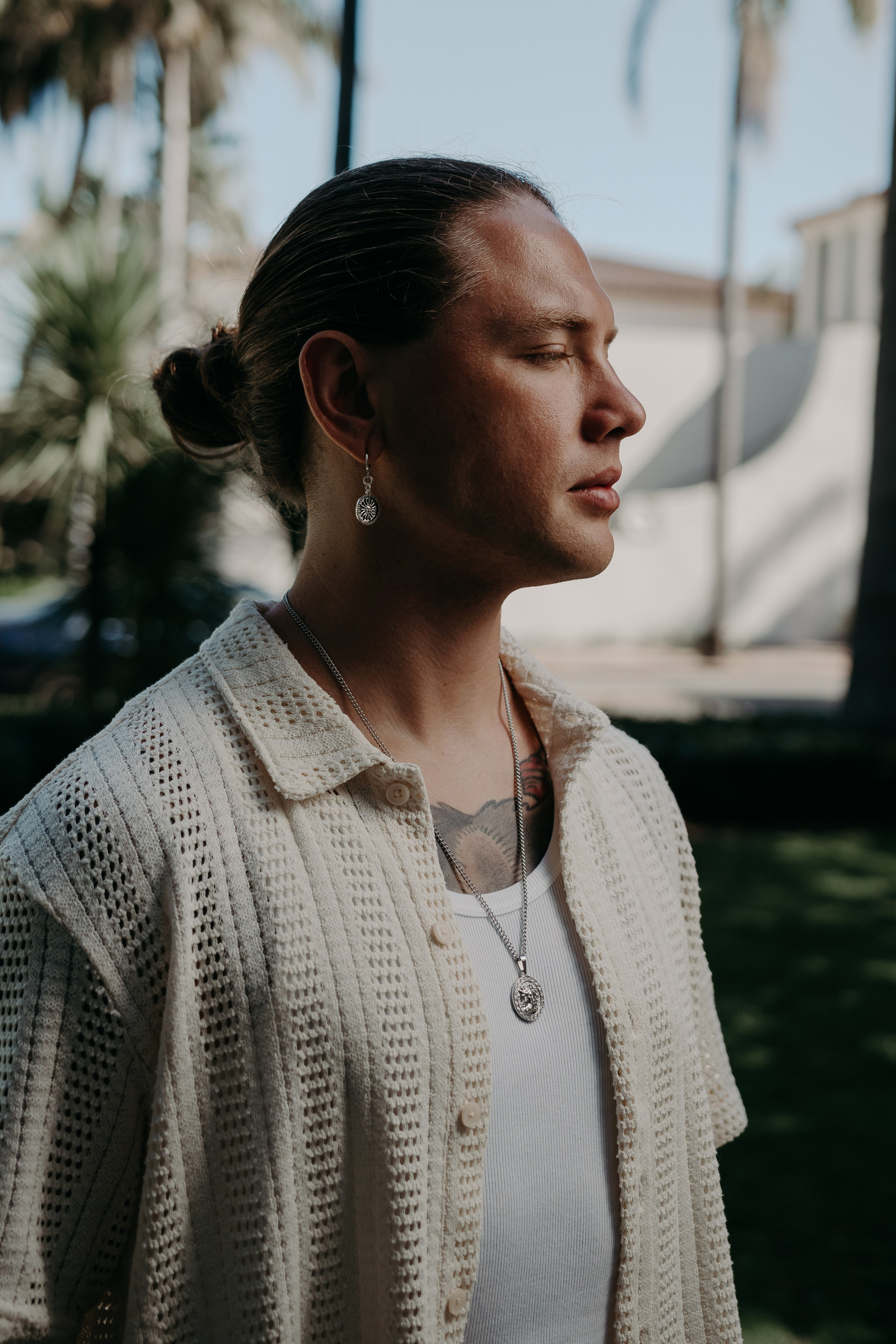 Male model styled in silver jewelry with natural lighting, blending casual and formal aesthetics.