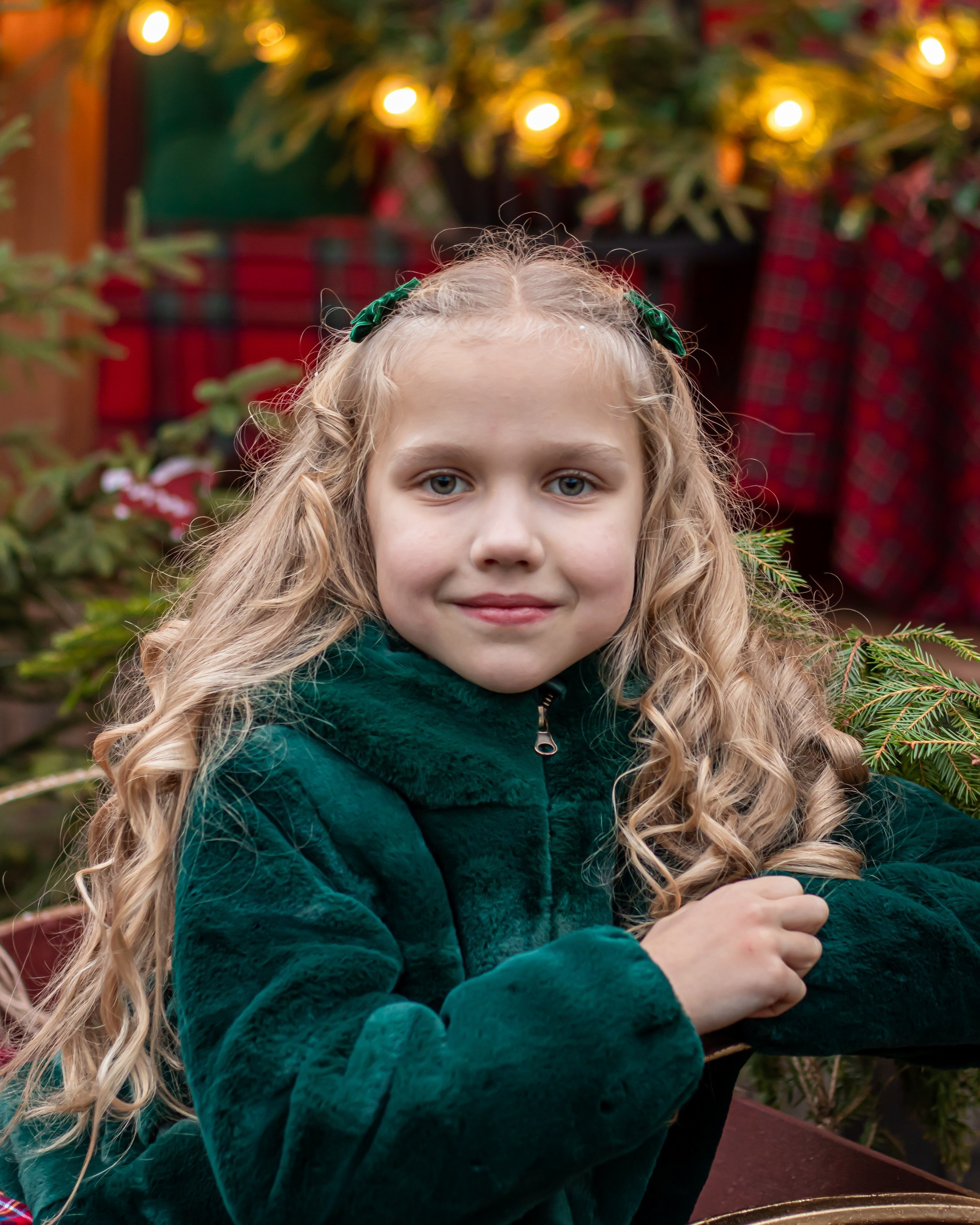 Девочка в зелёной улыбается на фоне рождественских огоньков, фотограф Карасёва Елена