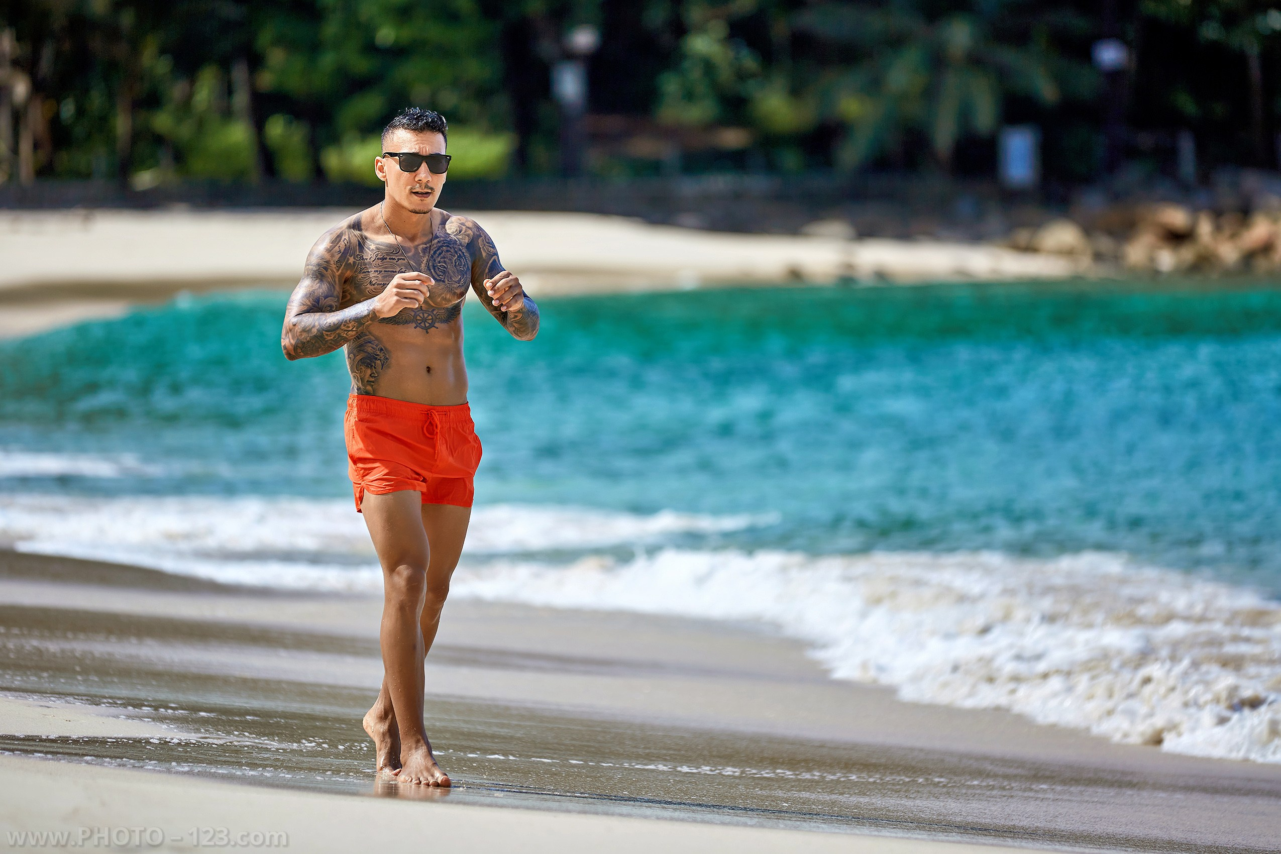 Athletic tattooed man running along the beach shoreline in Nha Trang captured by local photographer