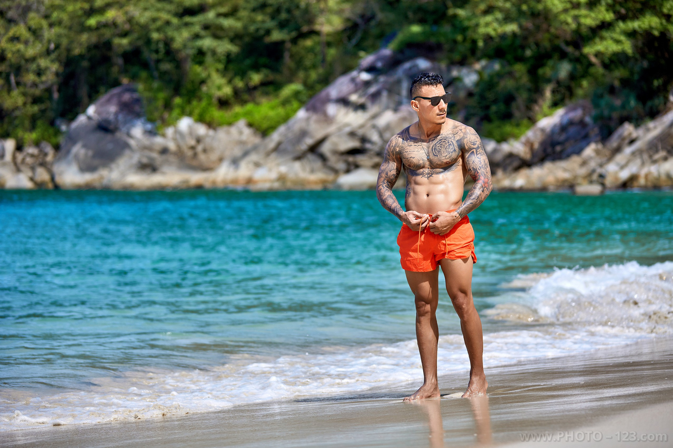 Athletic tattooed man posing on a tropical beach shore in Nha Trang by local photographer