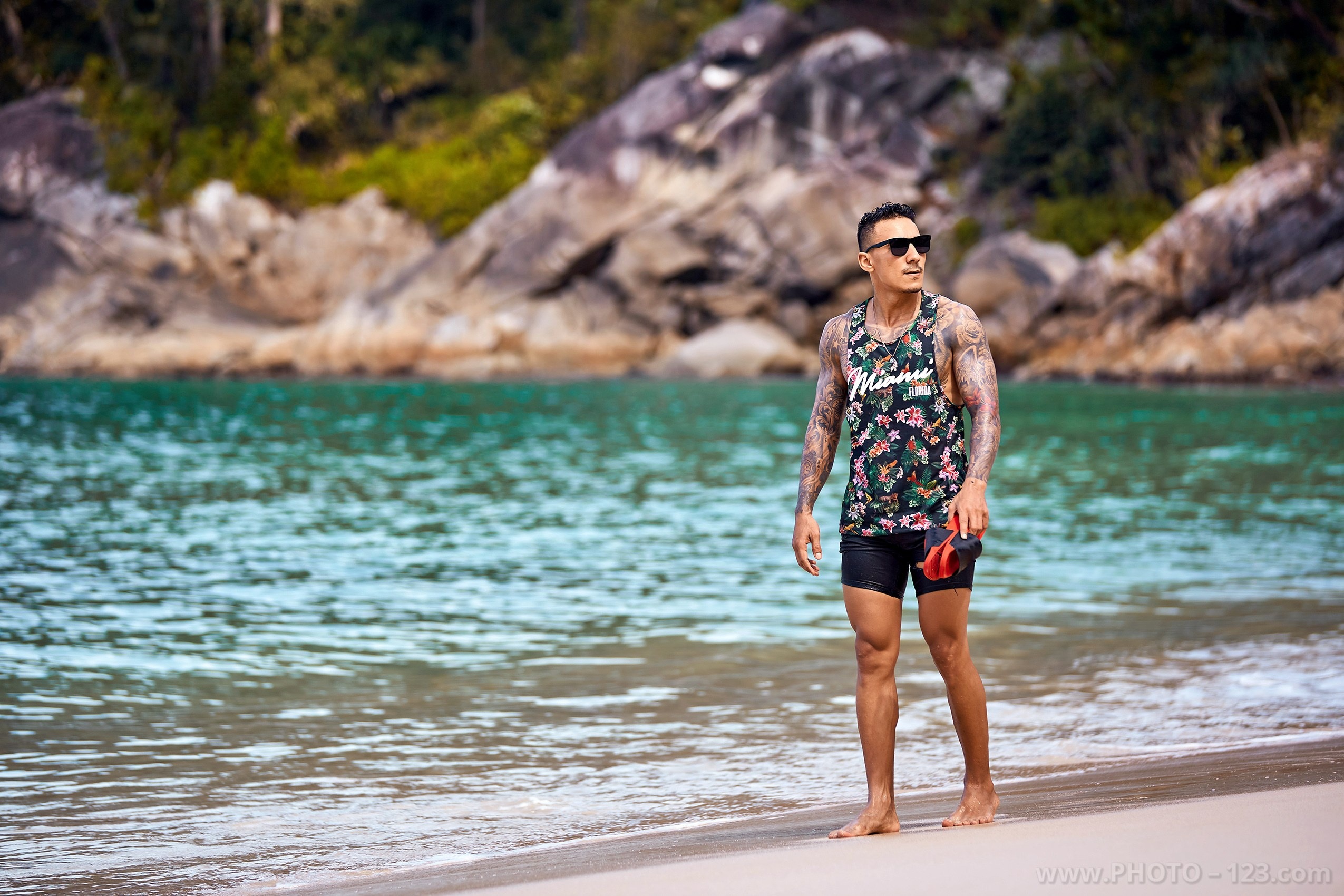 Athletic man in floral tank top walking on the beach in Nha Trang captured by professional photographer