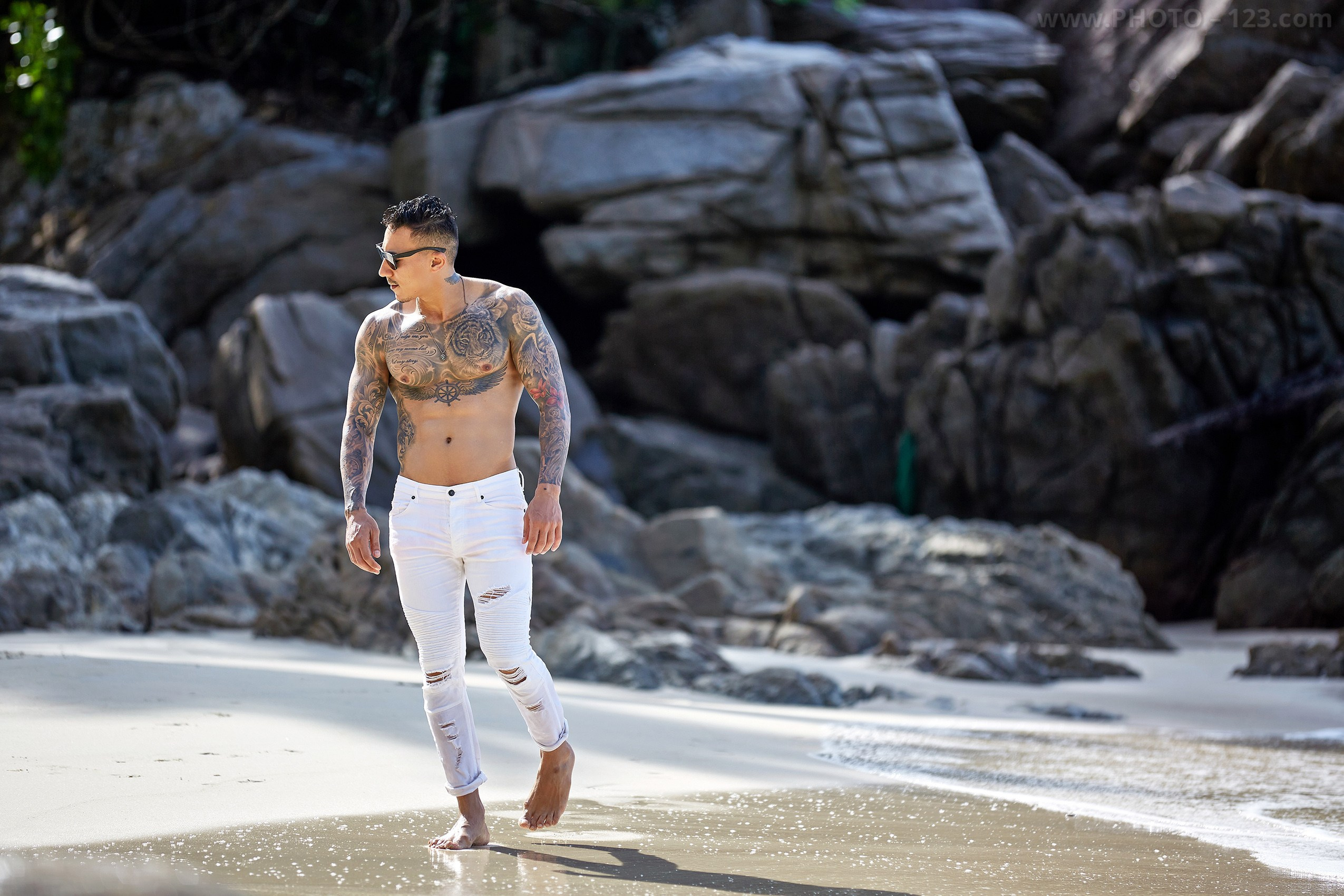 Shirtless male model pacing along the water's edge captured by professional Nha Trang photographer
