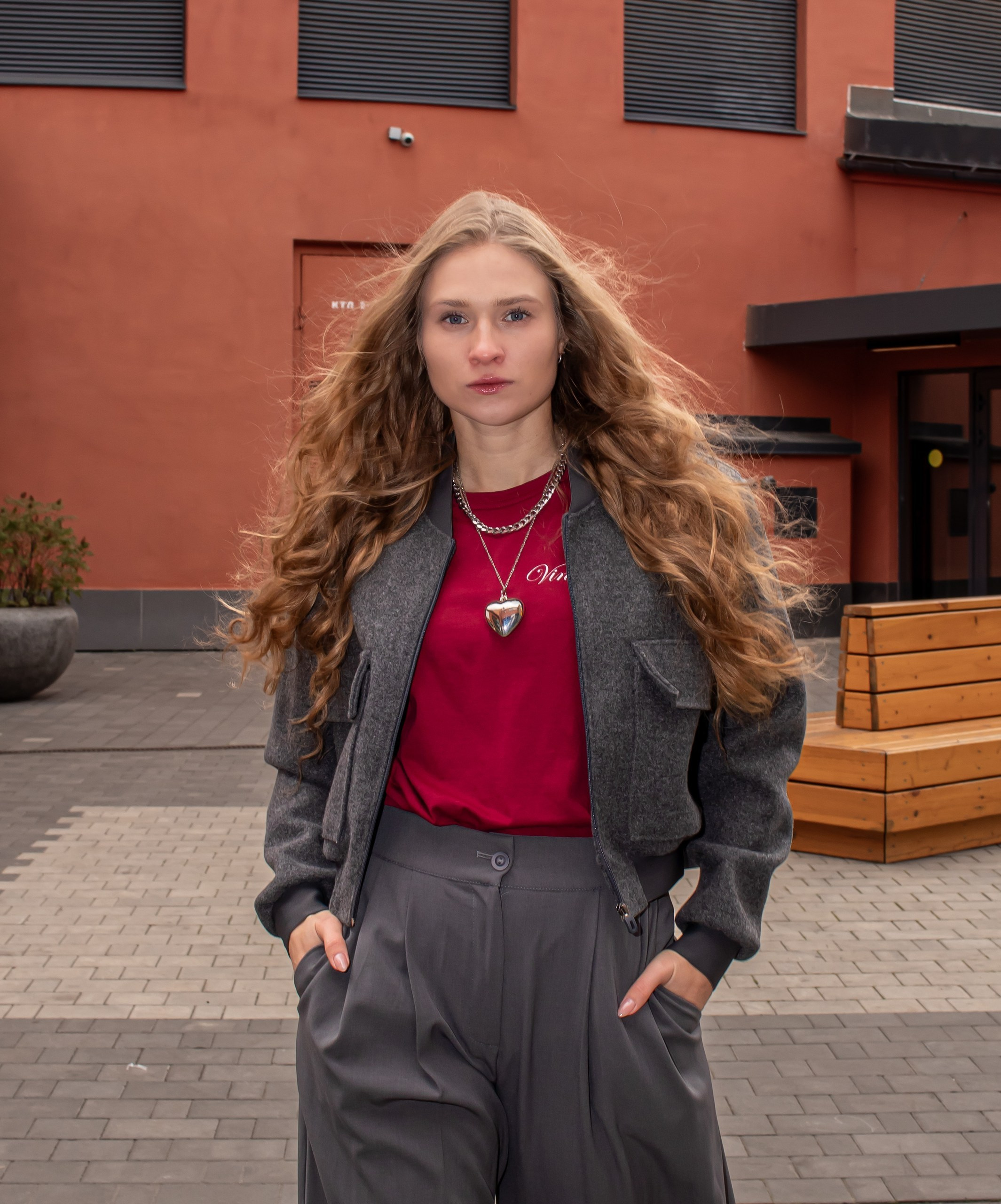 Портрет девушки в сером жакете и красной кофте на фоне индустриальной архитектуры — осенняя фотосессия