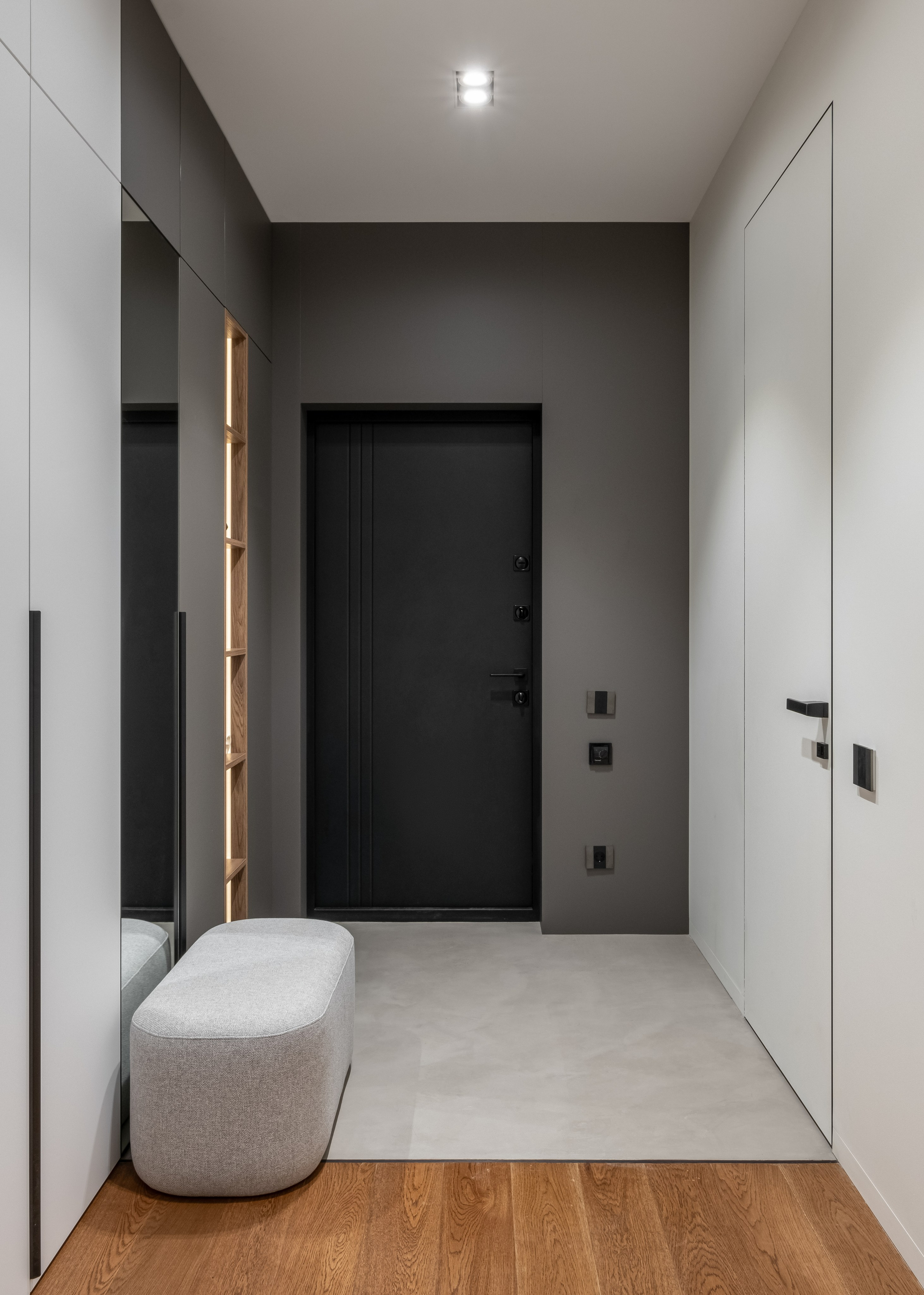 Интерьер прихожей с серыми стенами и мягкой банкеткой