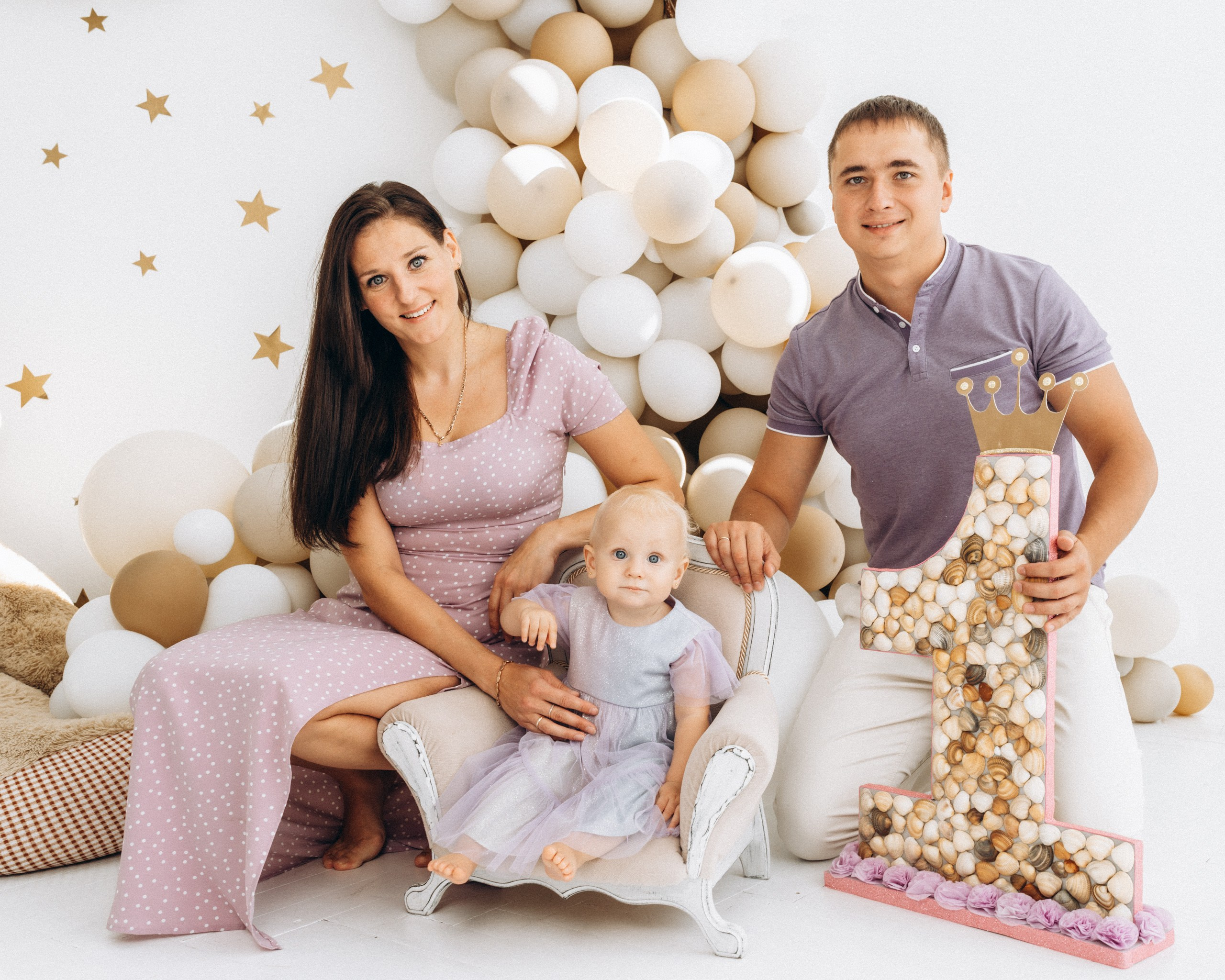 Папа и мама с годовалой дочкой в фотозоне с шарами на 1 годик