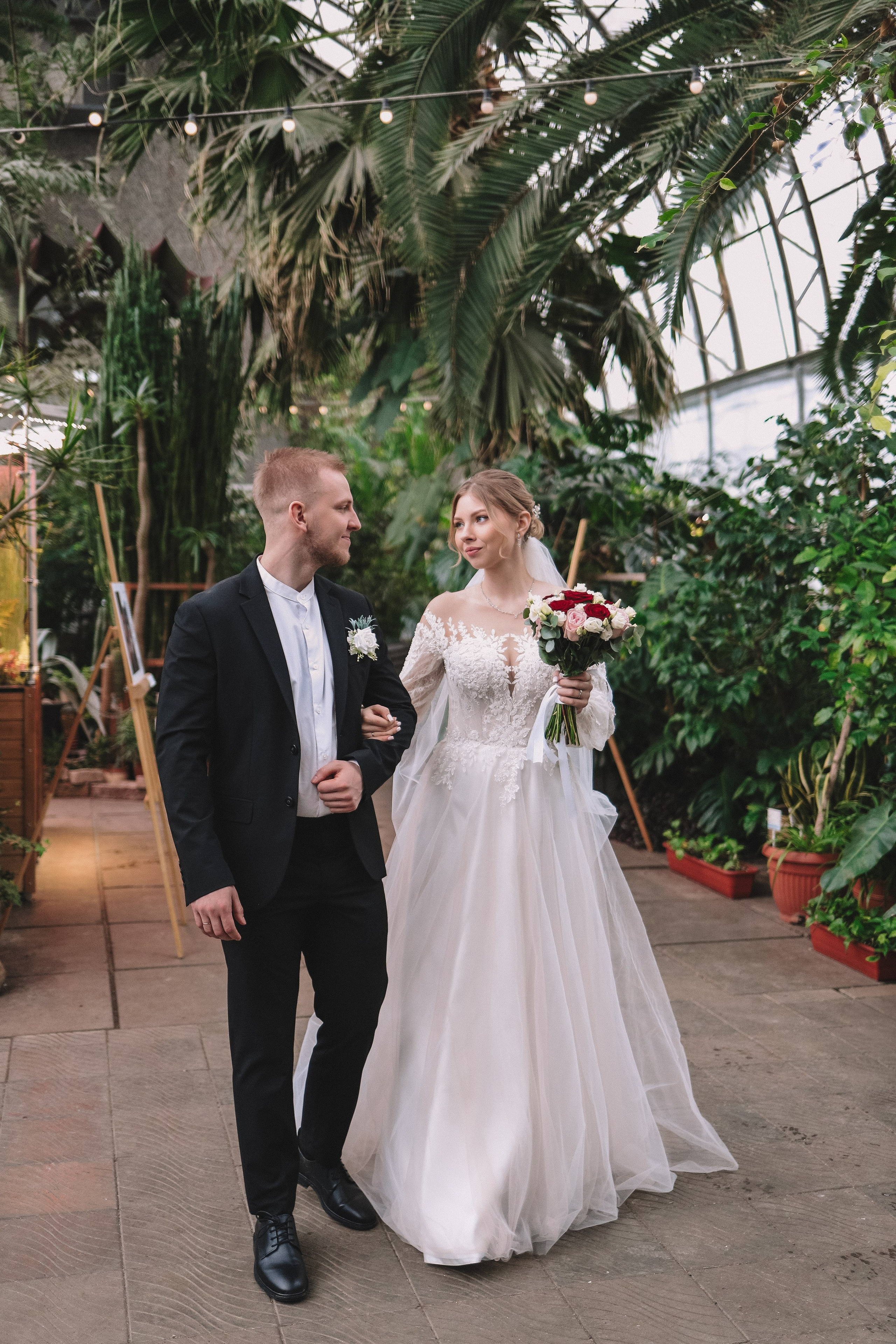 Молодожены идут по оранжерее, прогулка после свадьбы