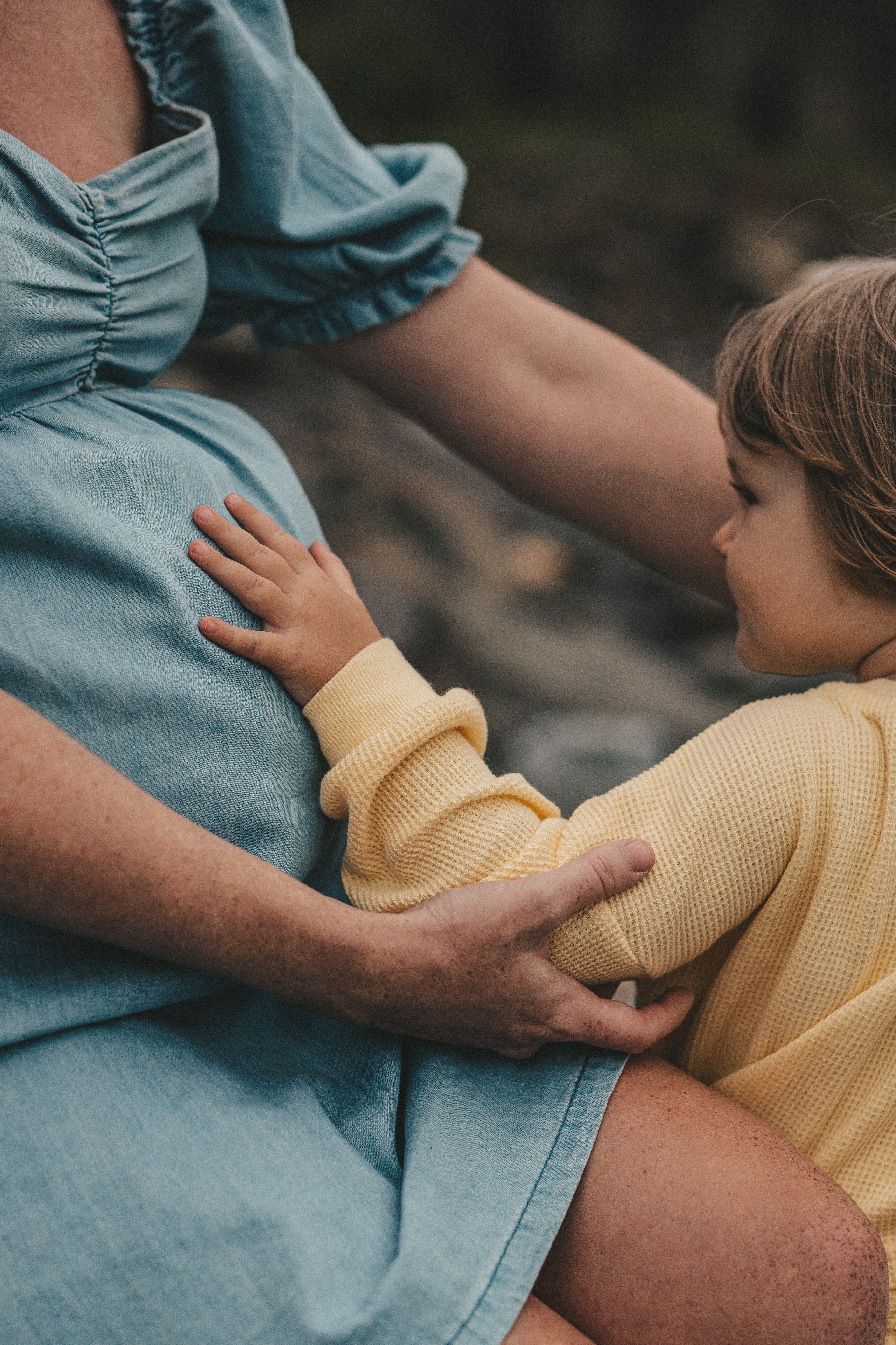маленькая девочка трогает мамин беременный живот