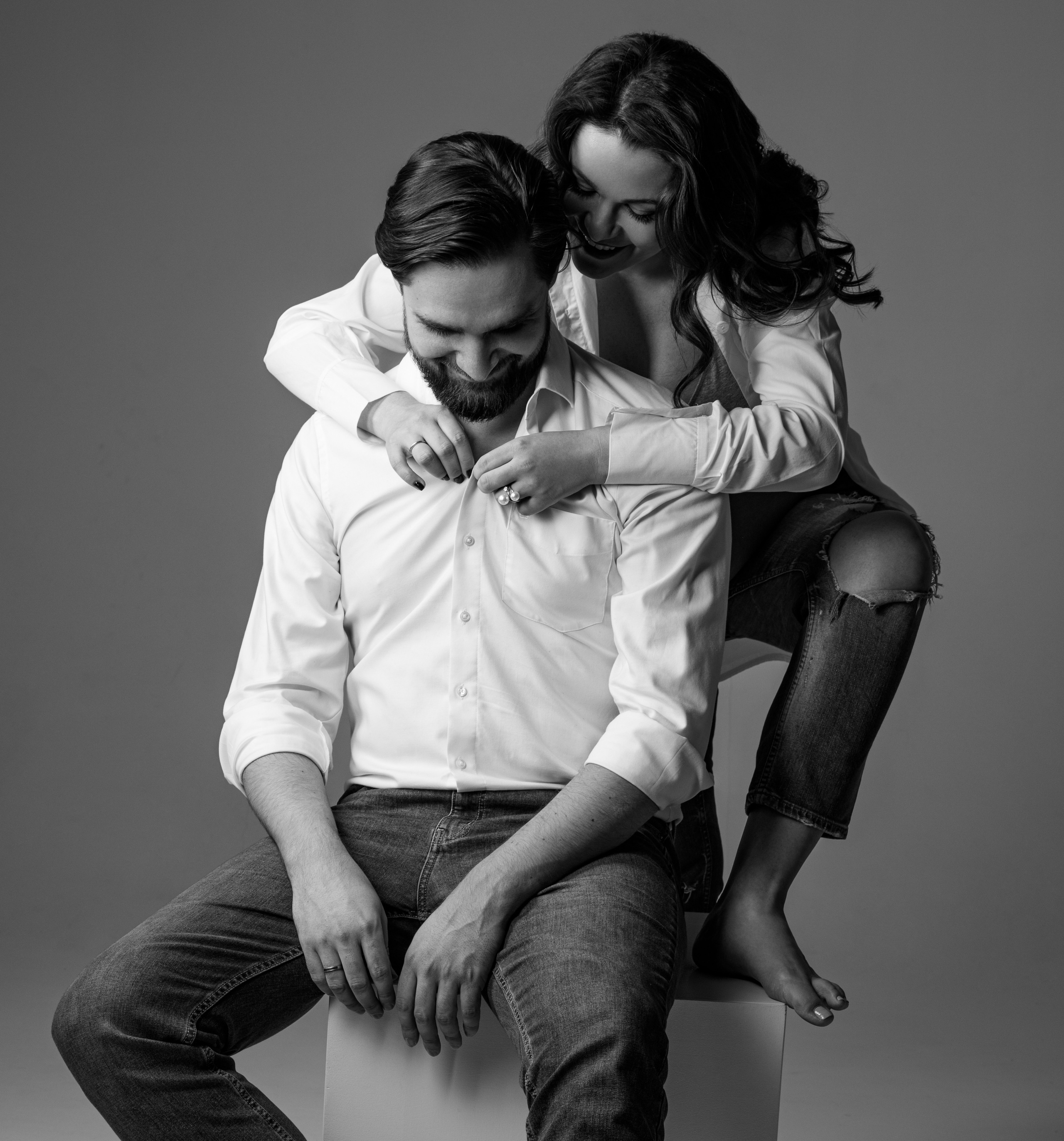 Черно-белая фотосессия беременности с мужем на сером фоне.