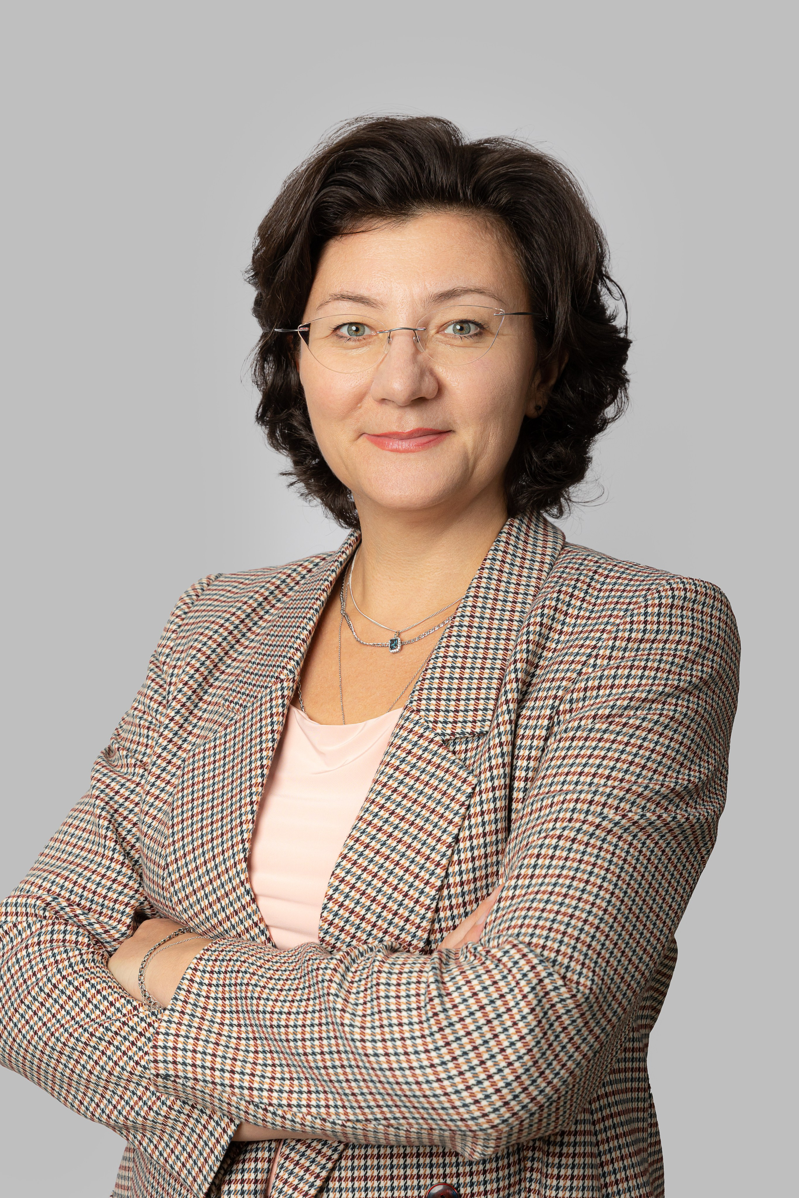 Женщина брюнетка в пиджаке и очках на сером фоне