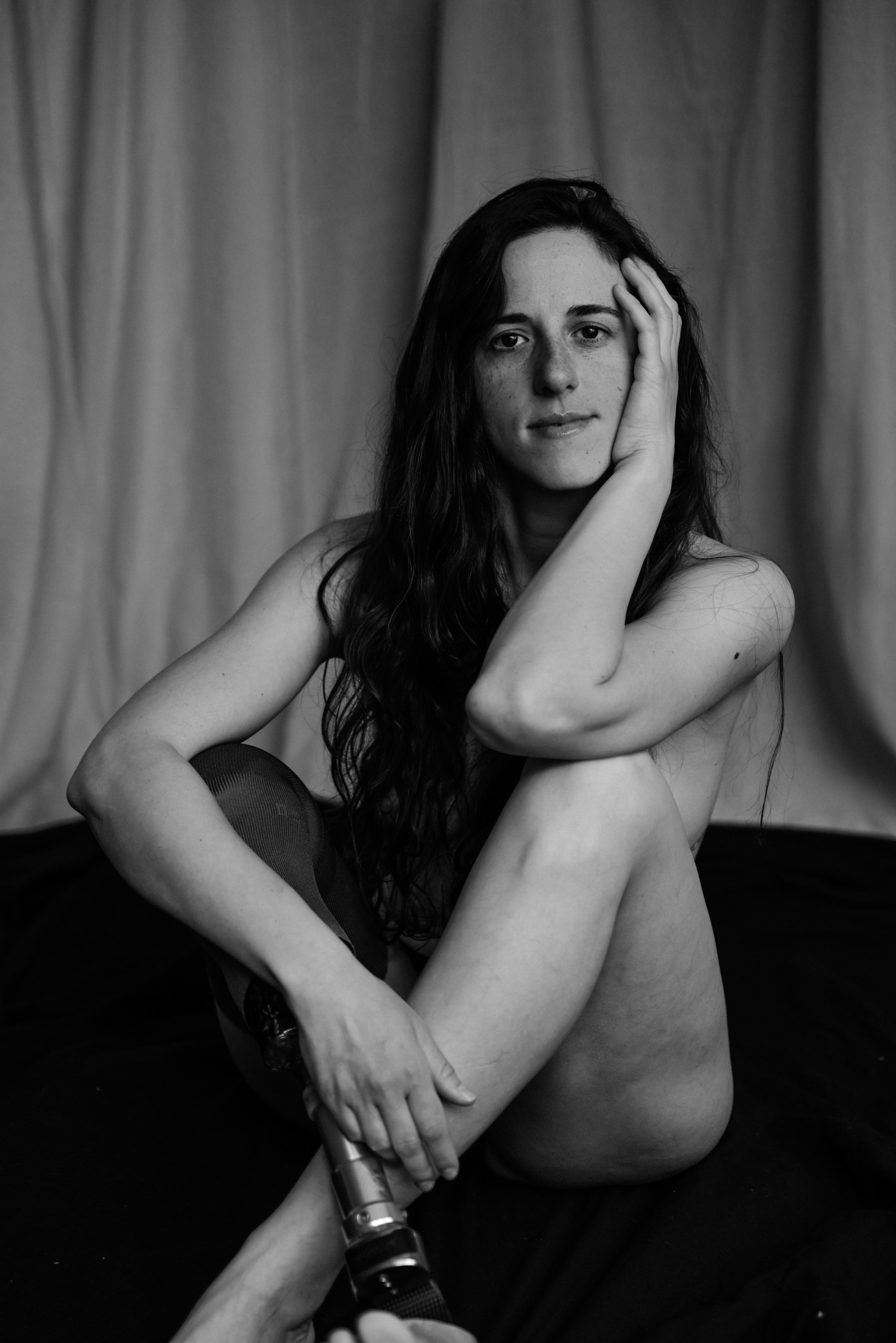 Boudoir portrait in London — black and white photo of a woman seated on the floor, showing confidence and beauty after leg amputation due to cancer