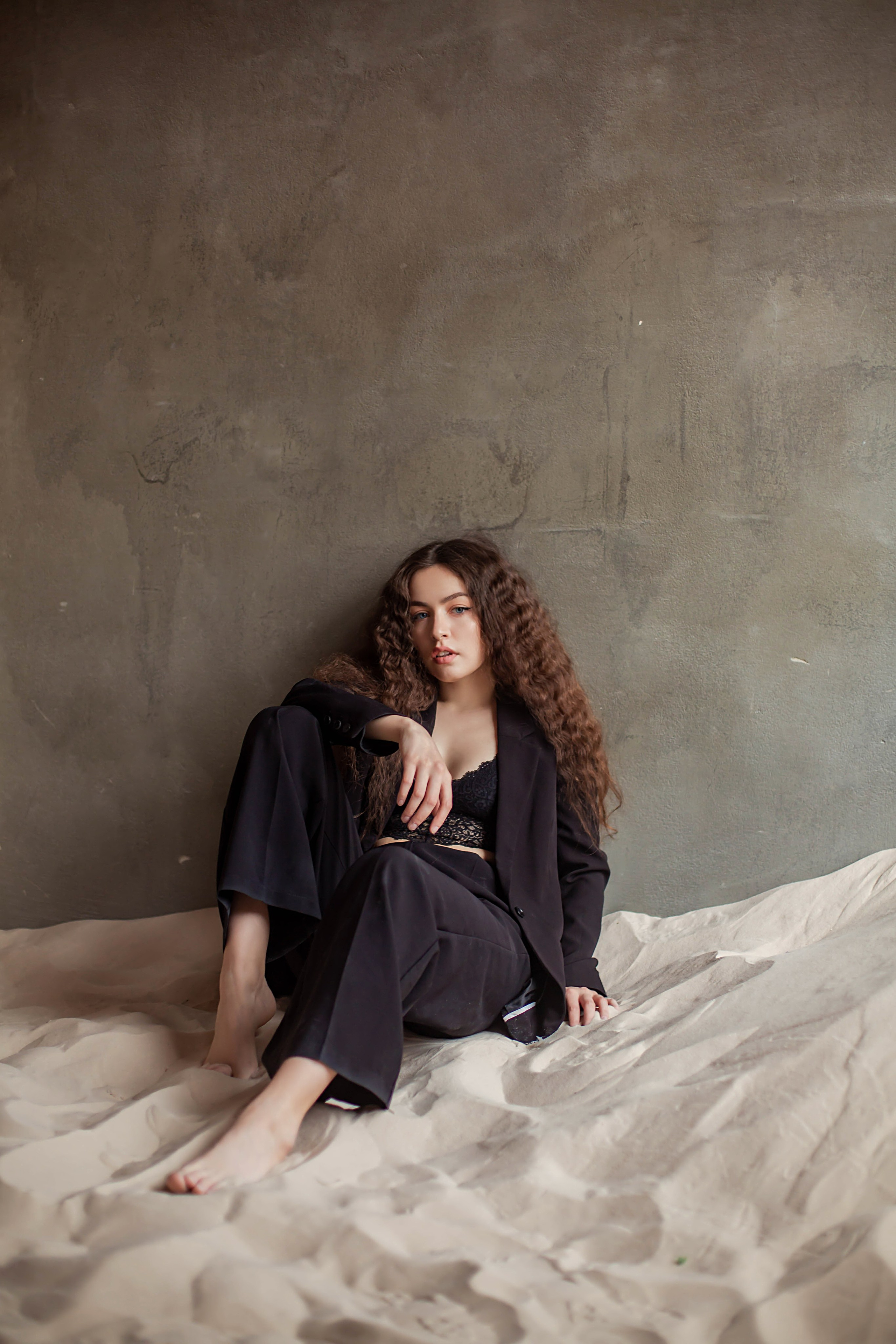 Ню фотосессия девушки в черных штанах и пиджаке на песке с босыми ногами, в студии СПБ