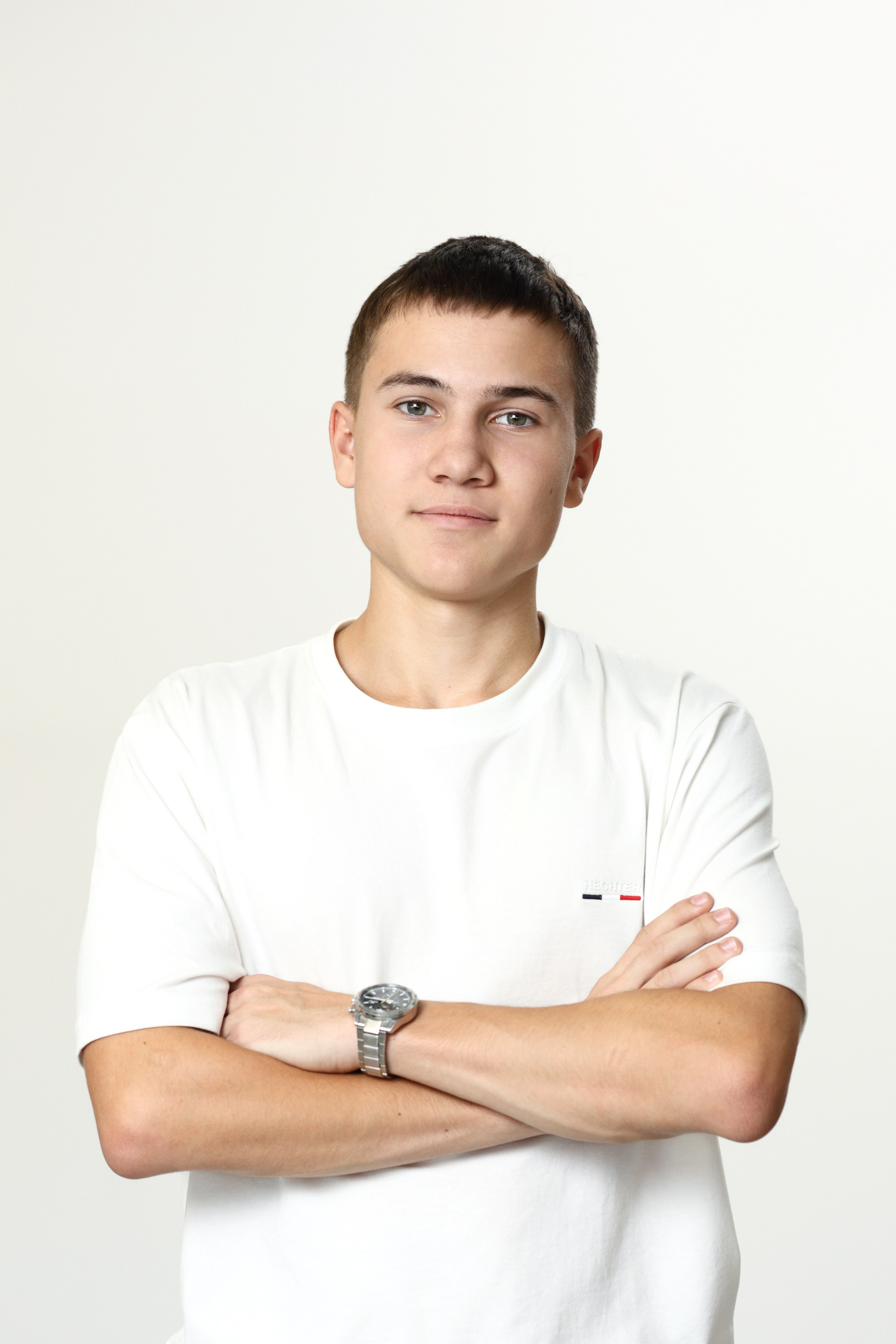 Портрет старшеклассника в белой футболке на светло-сером фоне в минималистичном стиле.