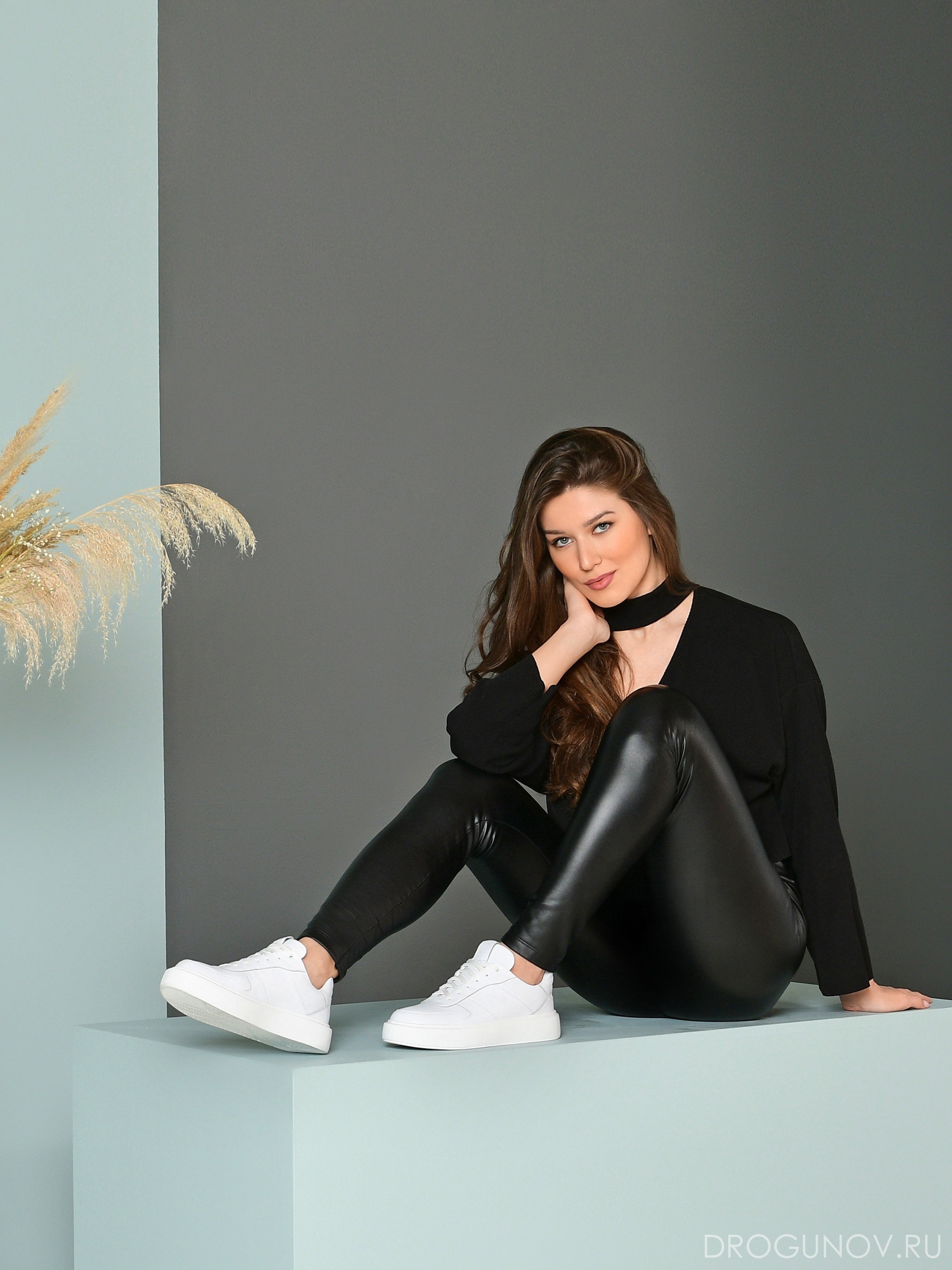 Фотомодель в кожаных брюках на цветом фоне.