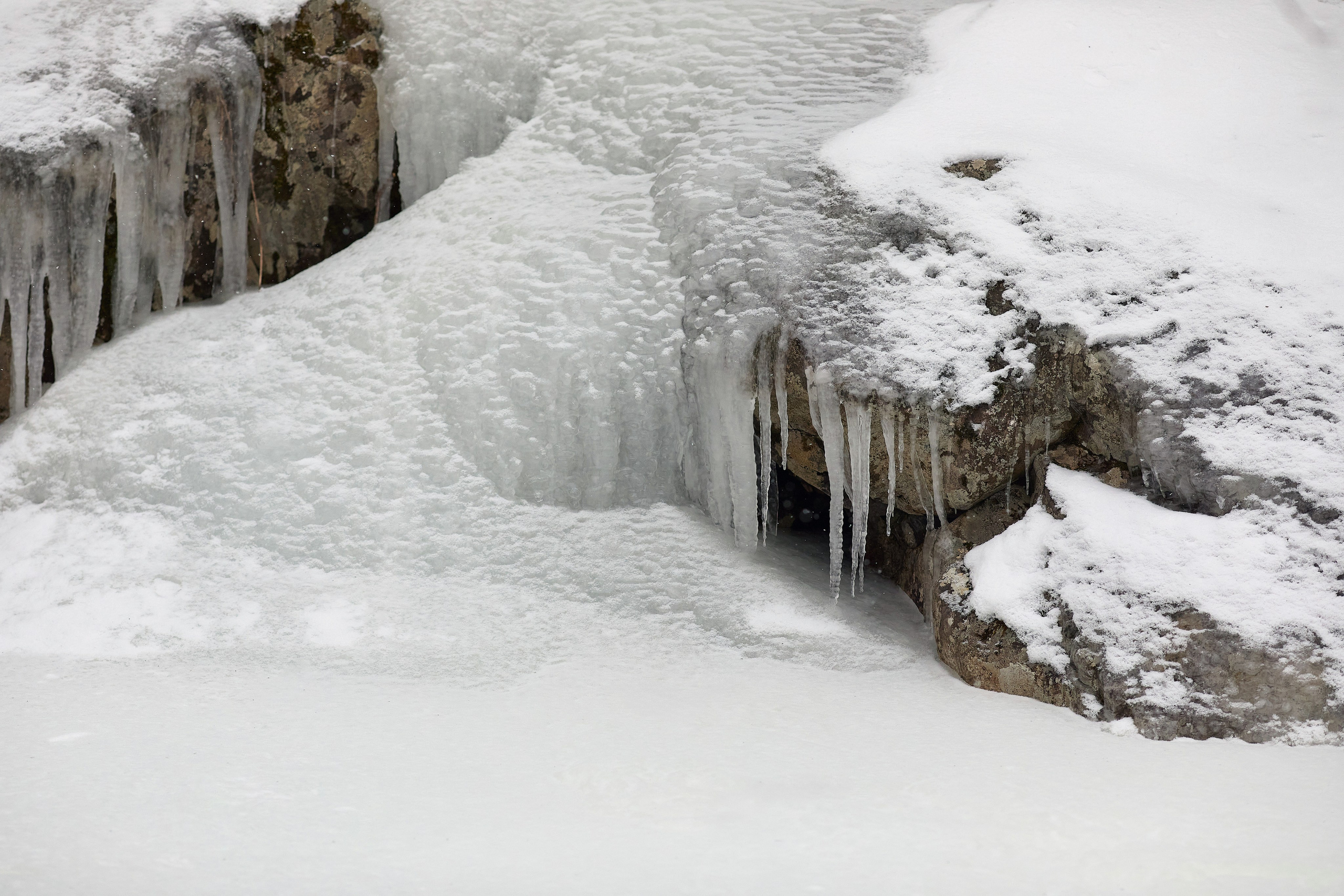 Снег, обледенелый берег реки и торчащие сосульки