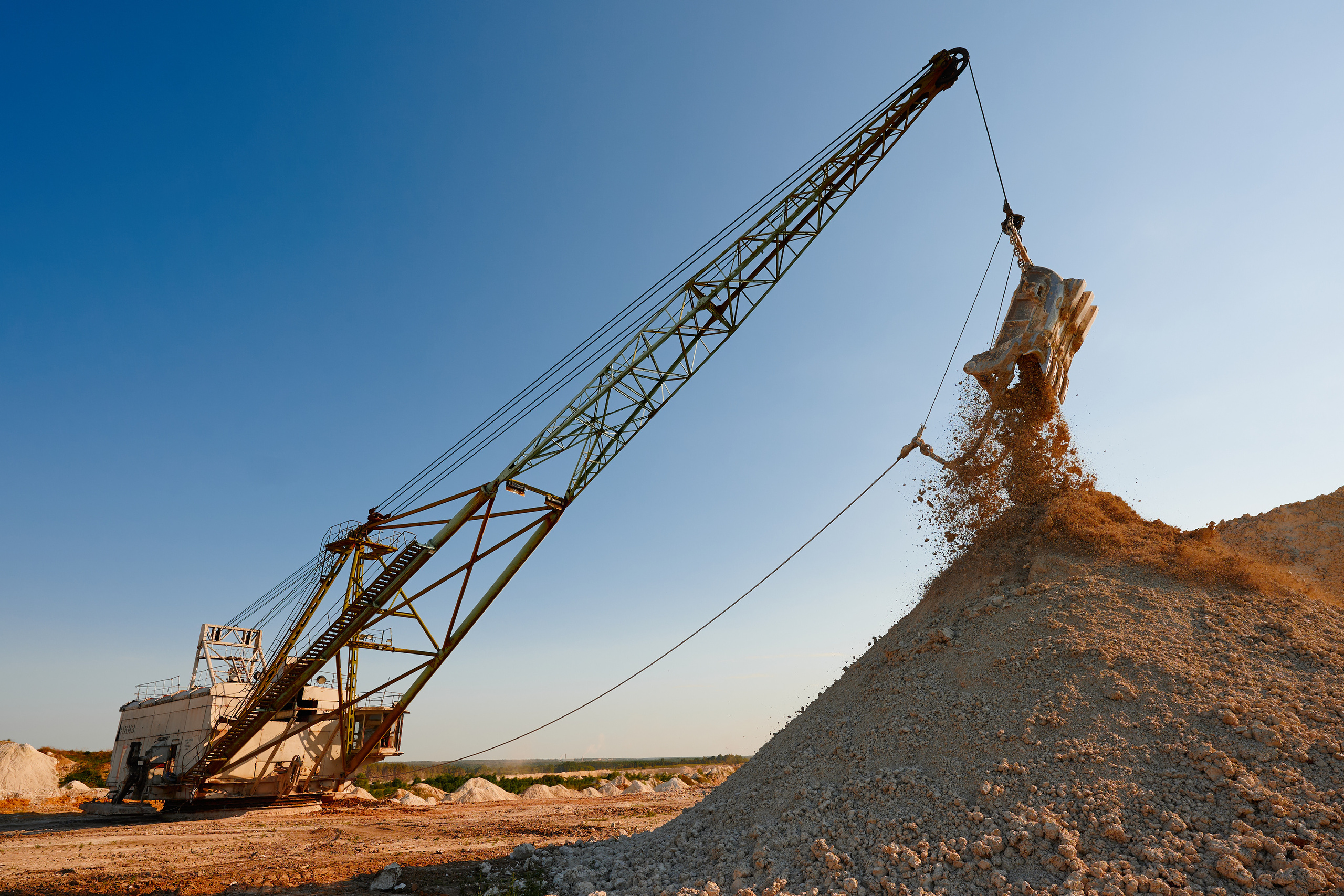 Драглайн высыпает грунт из ковша. Карьер по добыче мела