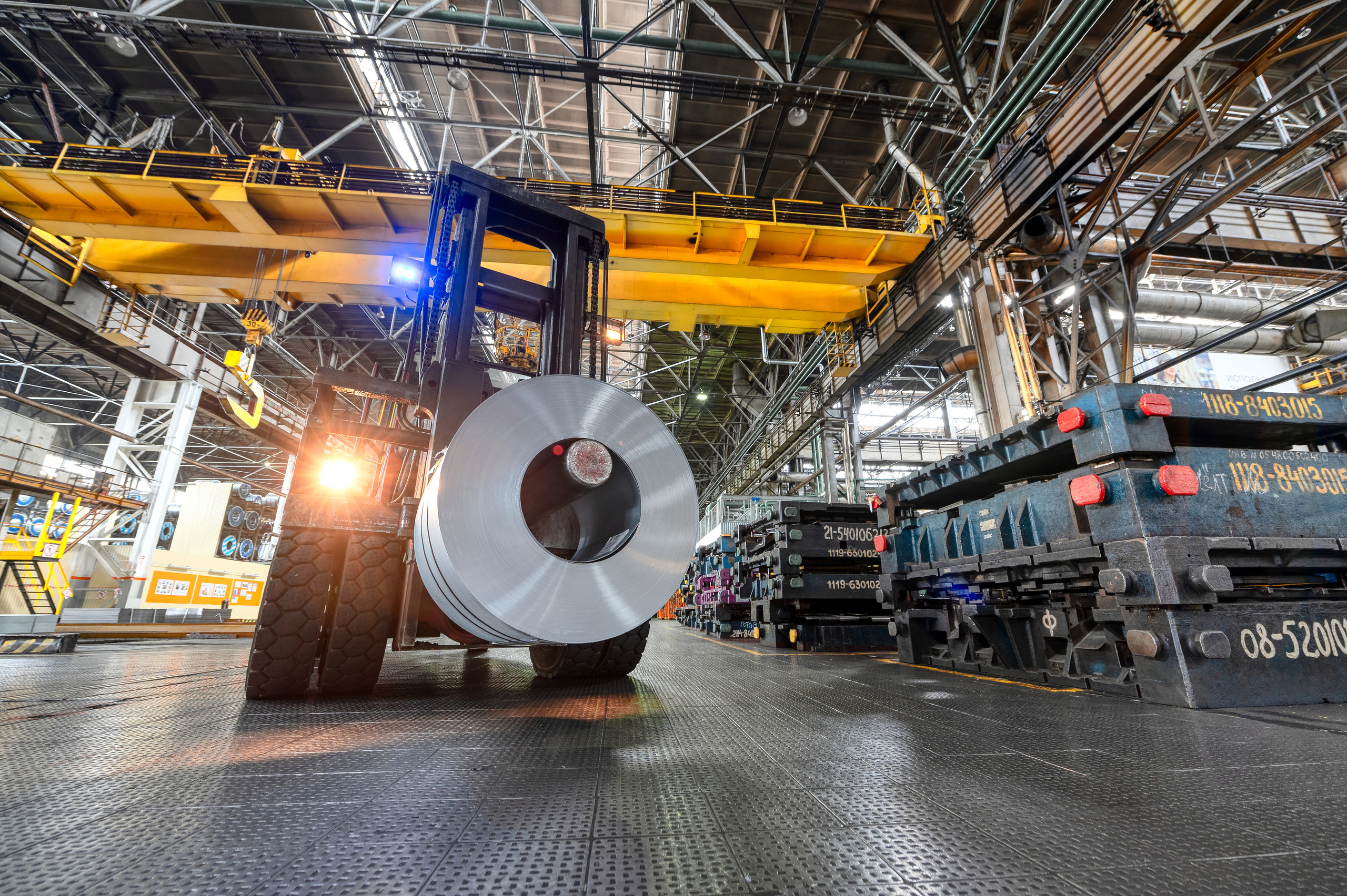 Вилочный погрузчик везет рулон стали по заводскому цеху