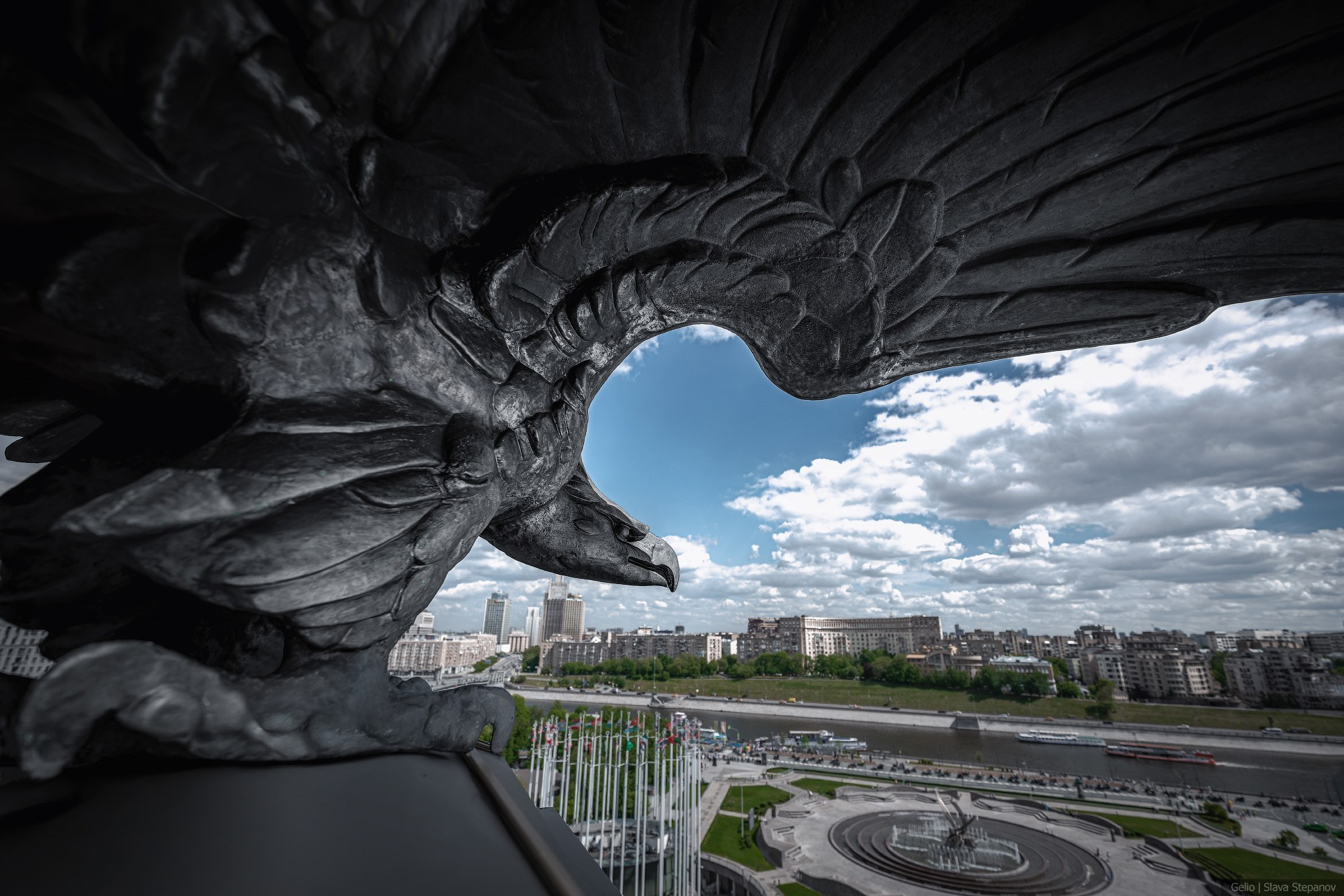 Close-up of a massive bronze eagle sculpture against a panorama of the Moskva River and dense urban development. Photographer Slava Stepanov.