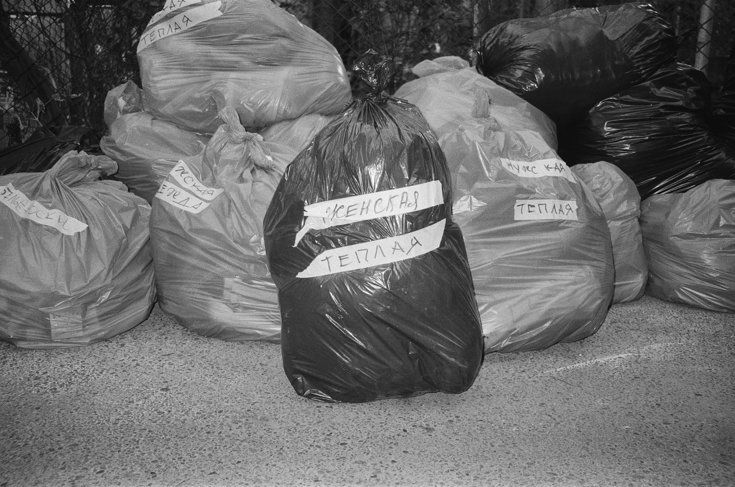 Garbage bags are being used to store donated clothing. The label on the bag reads "Women's. Warm."