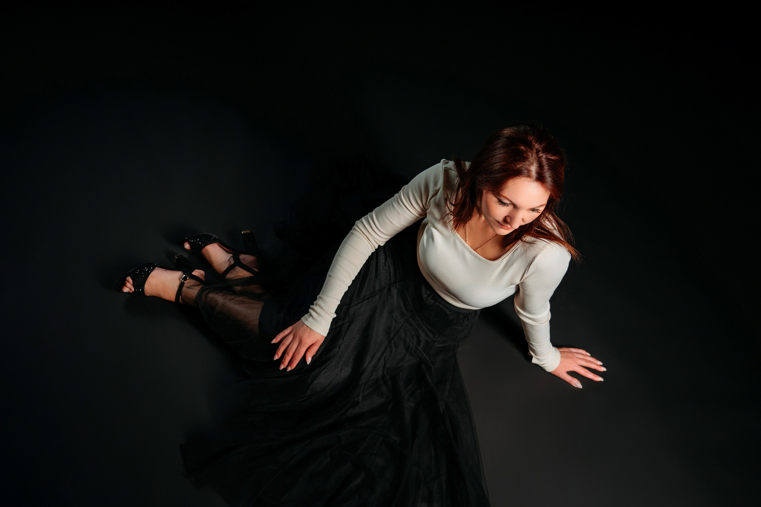 Женщина позирует в студии на черном фоне, вид сверху