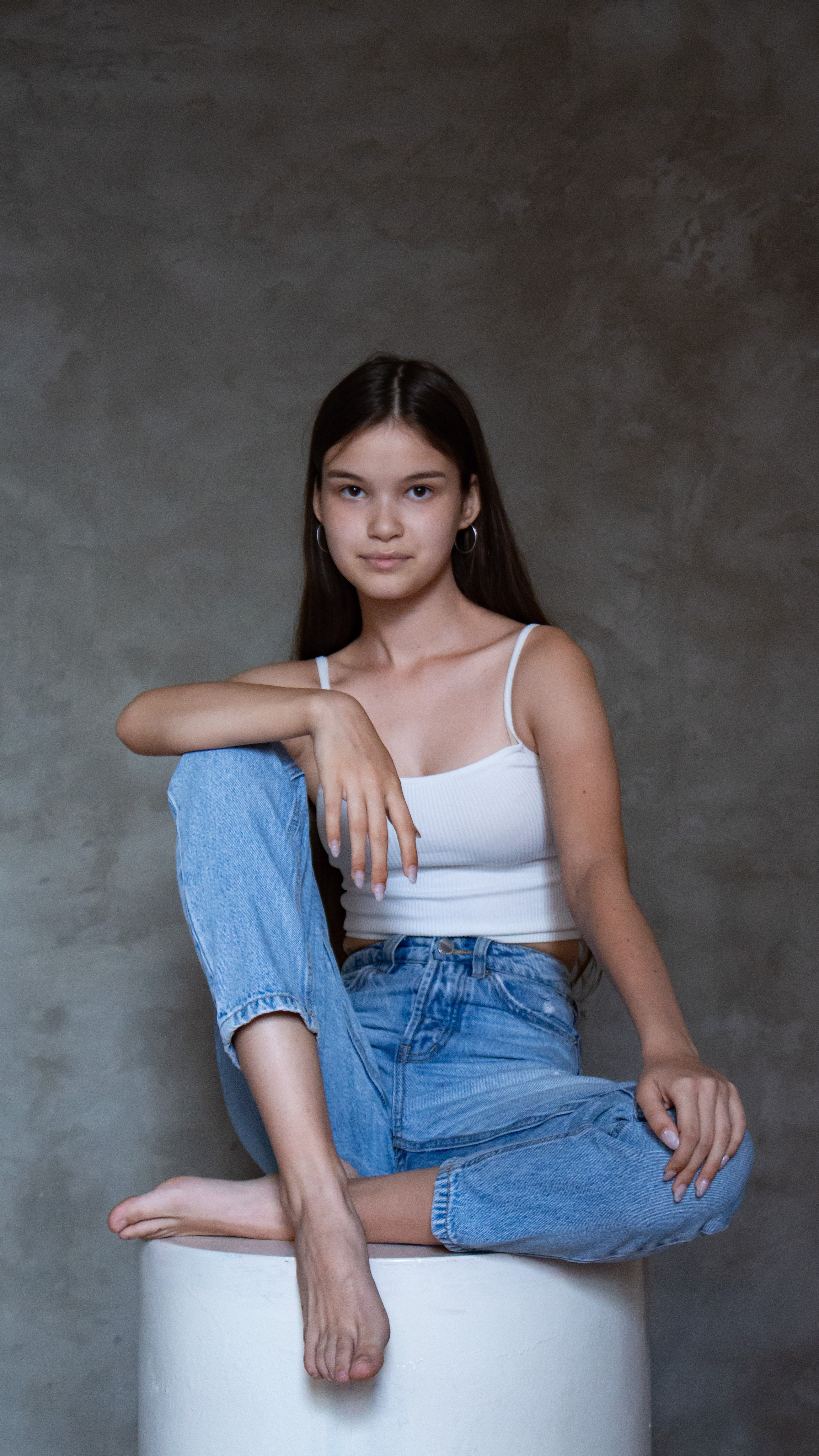 Девушка сидит на пуфе, скрестив ноги. Студийная съёмка Астрахань.