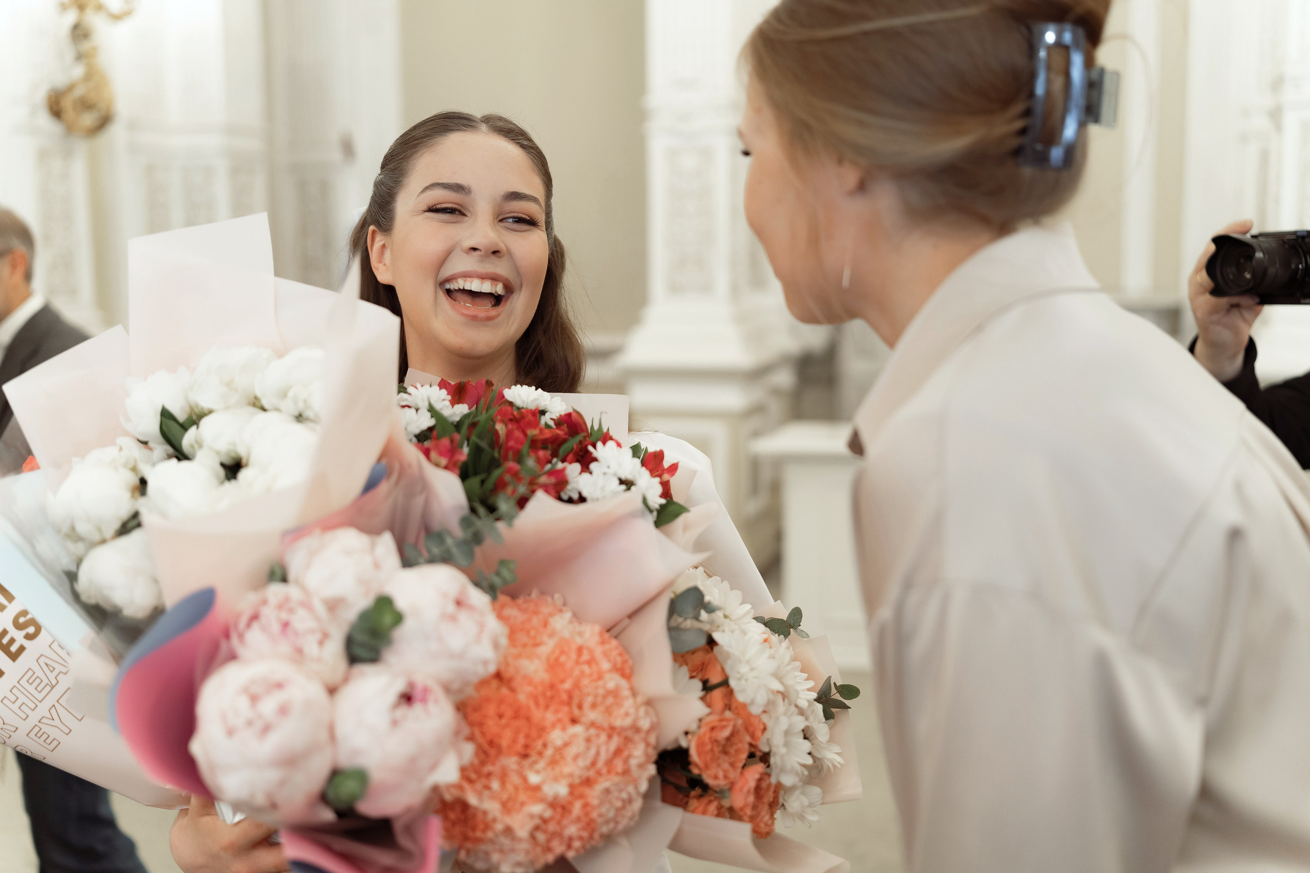 Счастливая невеста принимает букеты цветов от близких и друзей