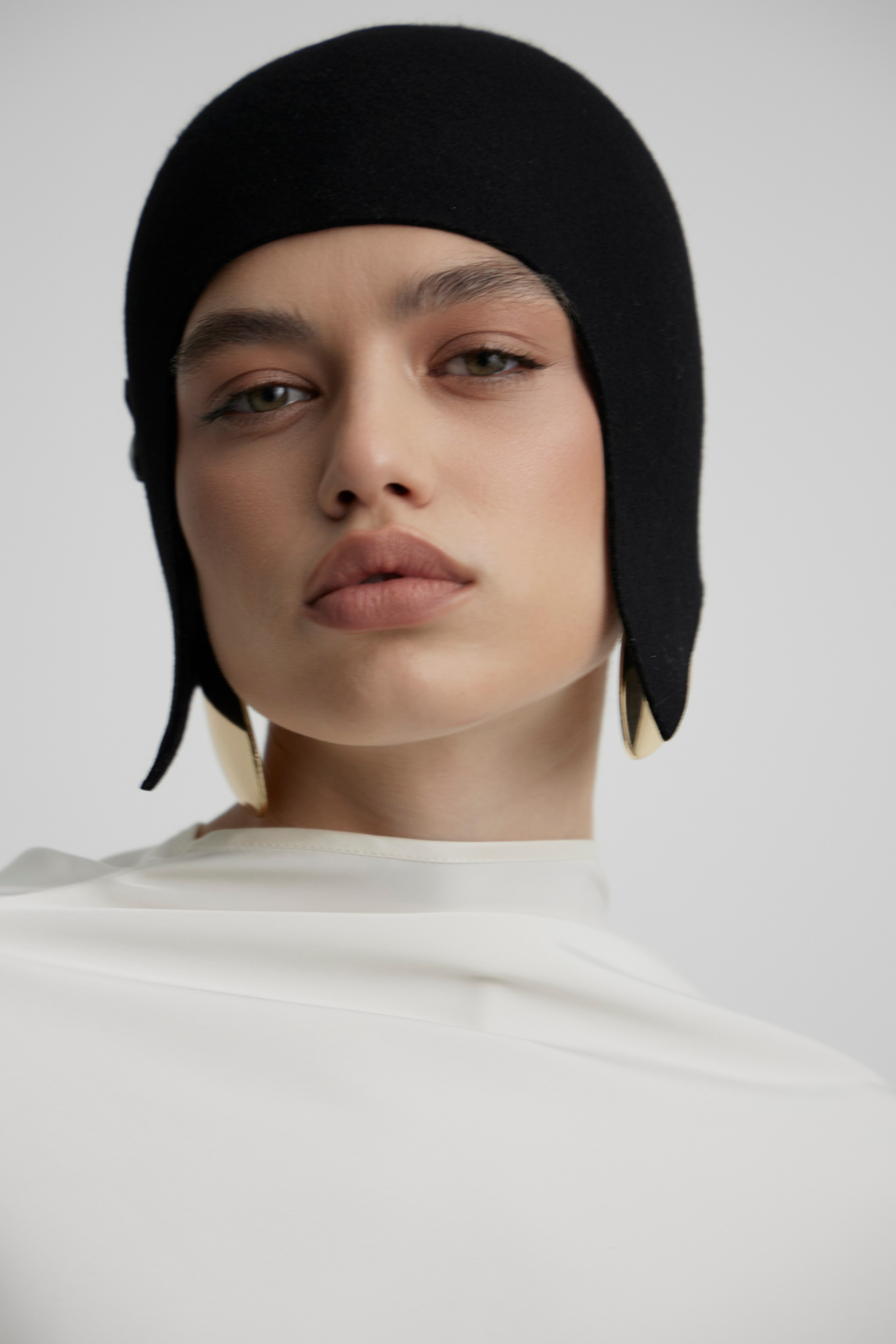 Close-up fashion campaign portrait of model wearing minimalist black headpiece photographed for contemporary fashion brand in Sydney studio