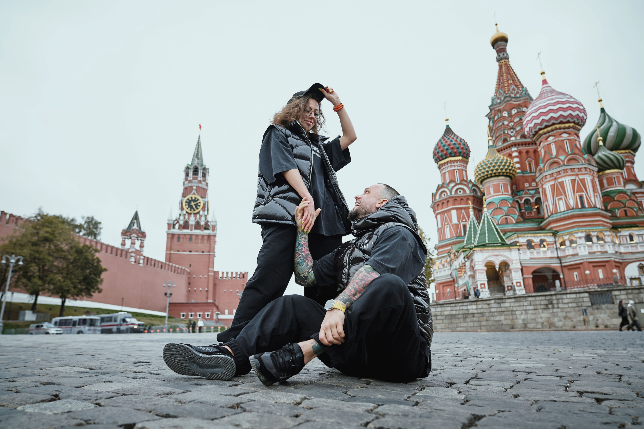 мужчина и женщина на красной площади в Москве сидят на брусчатке с видом на собор Василия блаженного