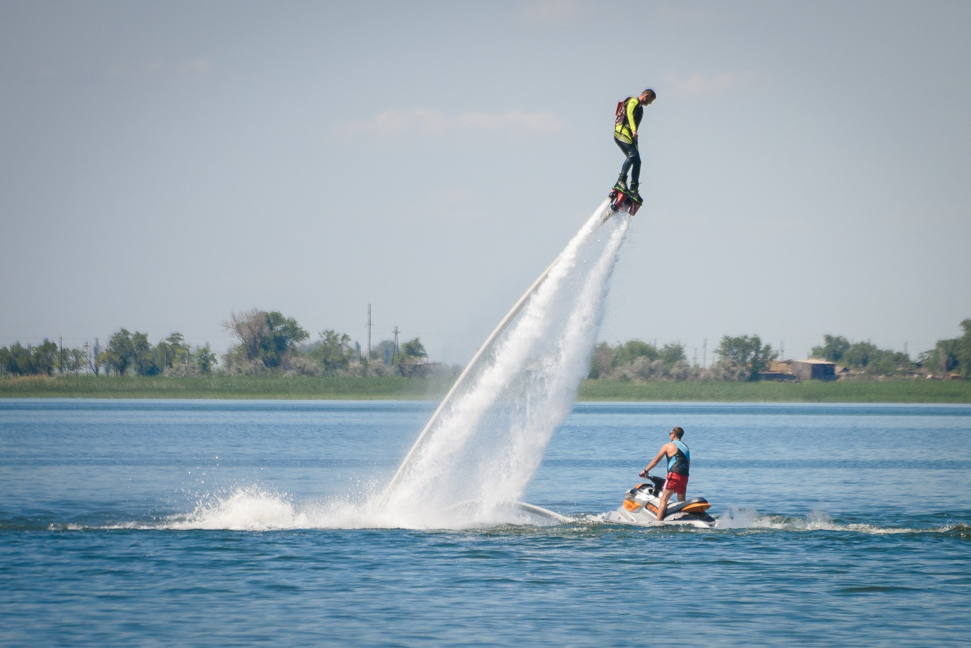 Мужчина на флайборде поднялся над водой и завис над гидроциклом