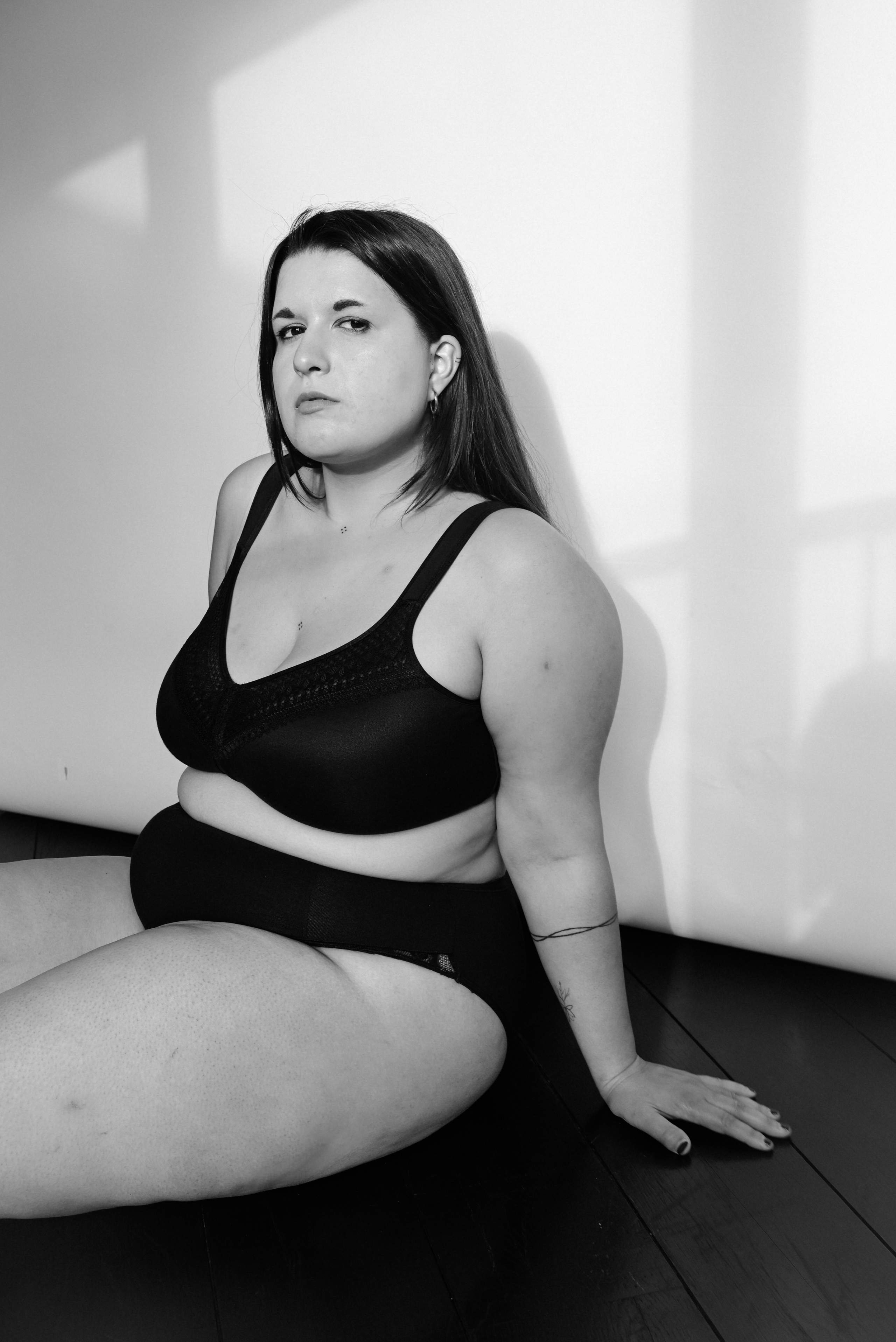 boudoir — plus size woman in lingerie seated on floor, relaxed confident pose