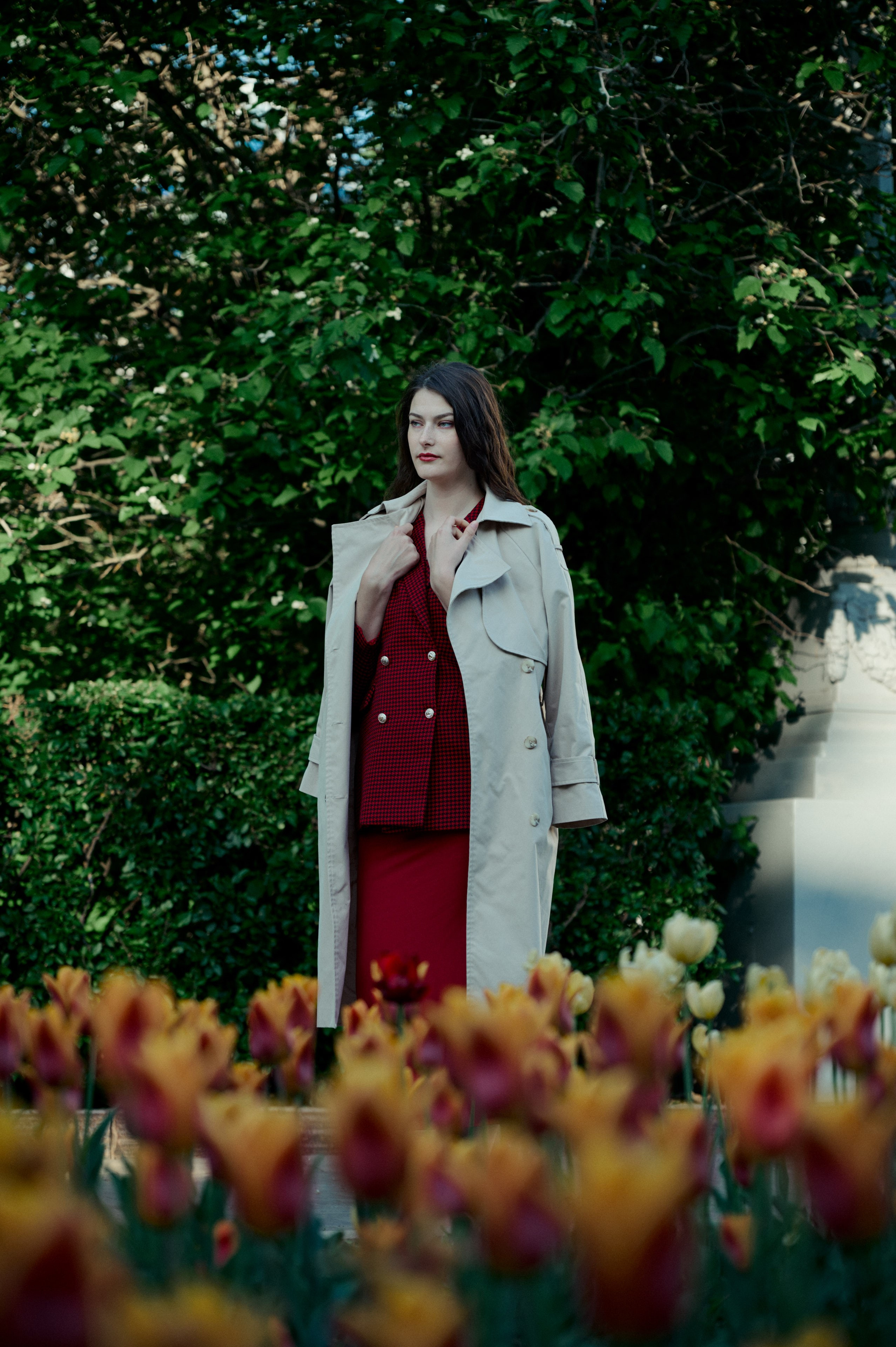 Весенняя фотосессия с цветами: женщина в классическом пальто среди пёстрых тюльпанов на фоне зелени.