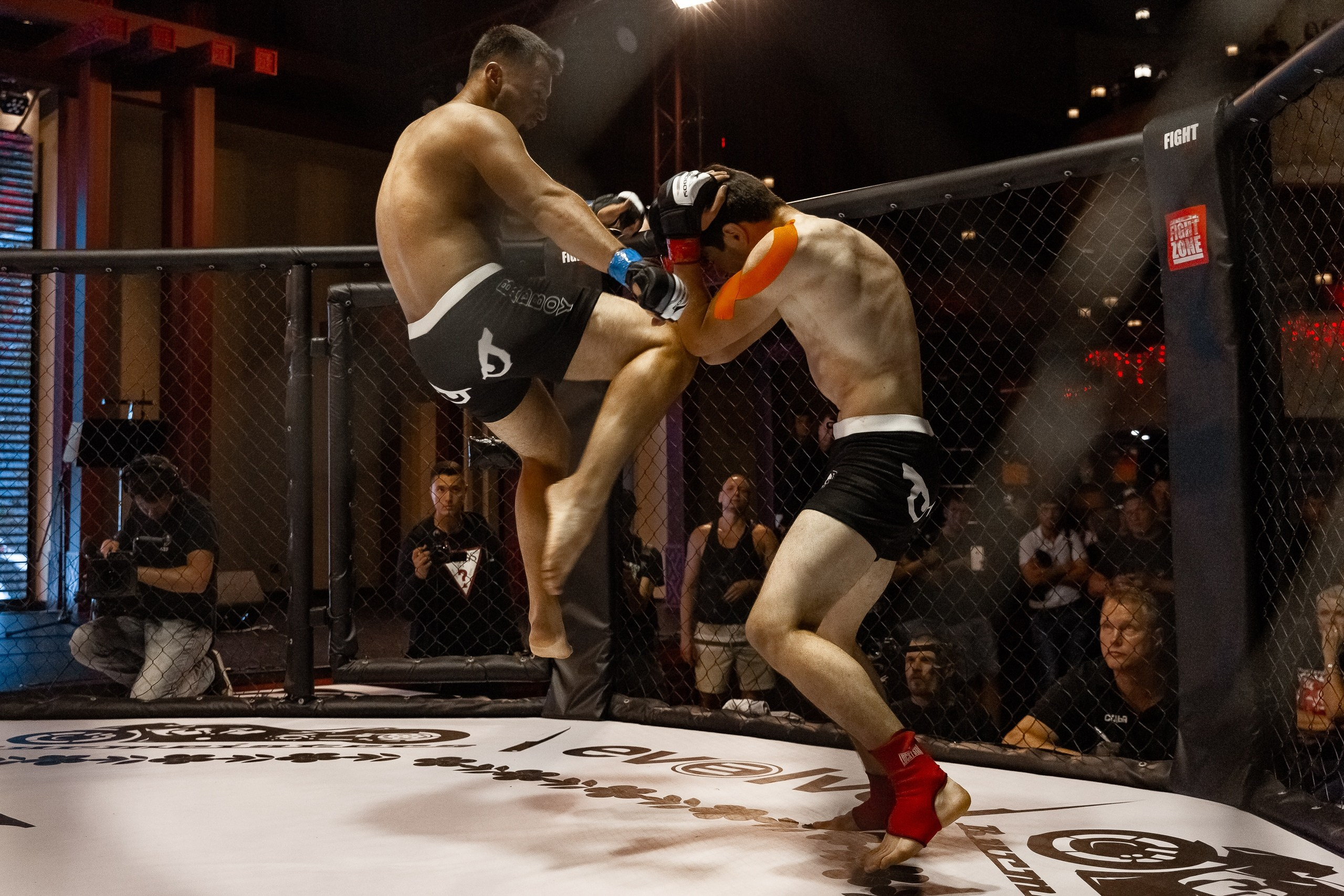 Удар коленом в воздухе в октагоне MMA репортажная фотография