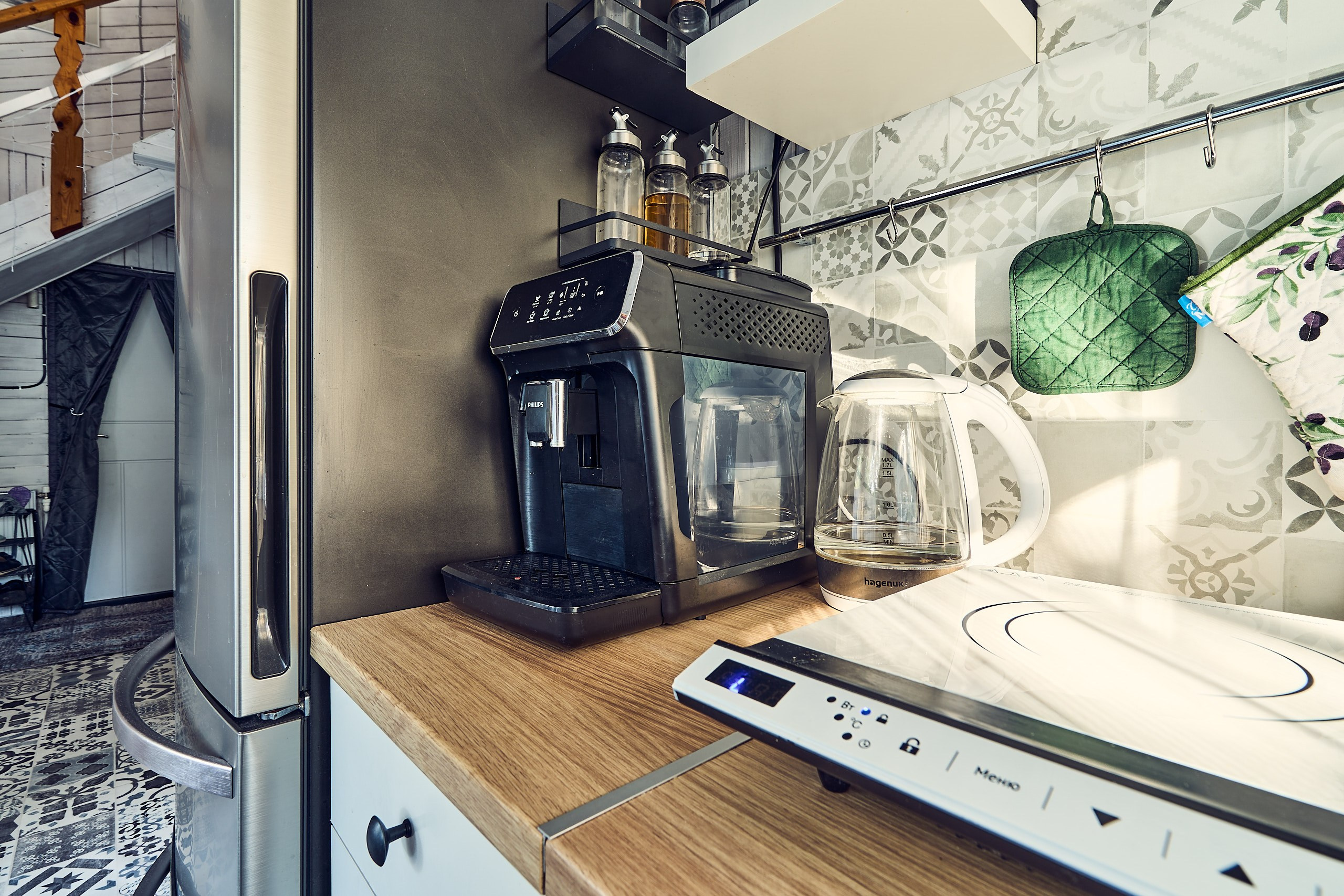 Интерьерная фотография с индукционной плитой, кофемашиной, прихватками и специями