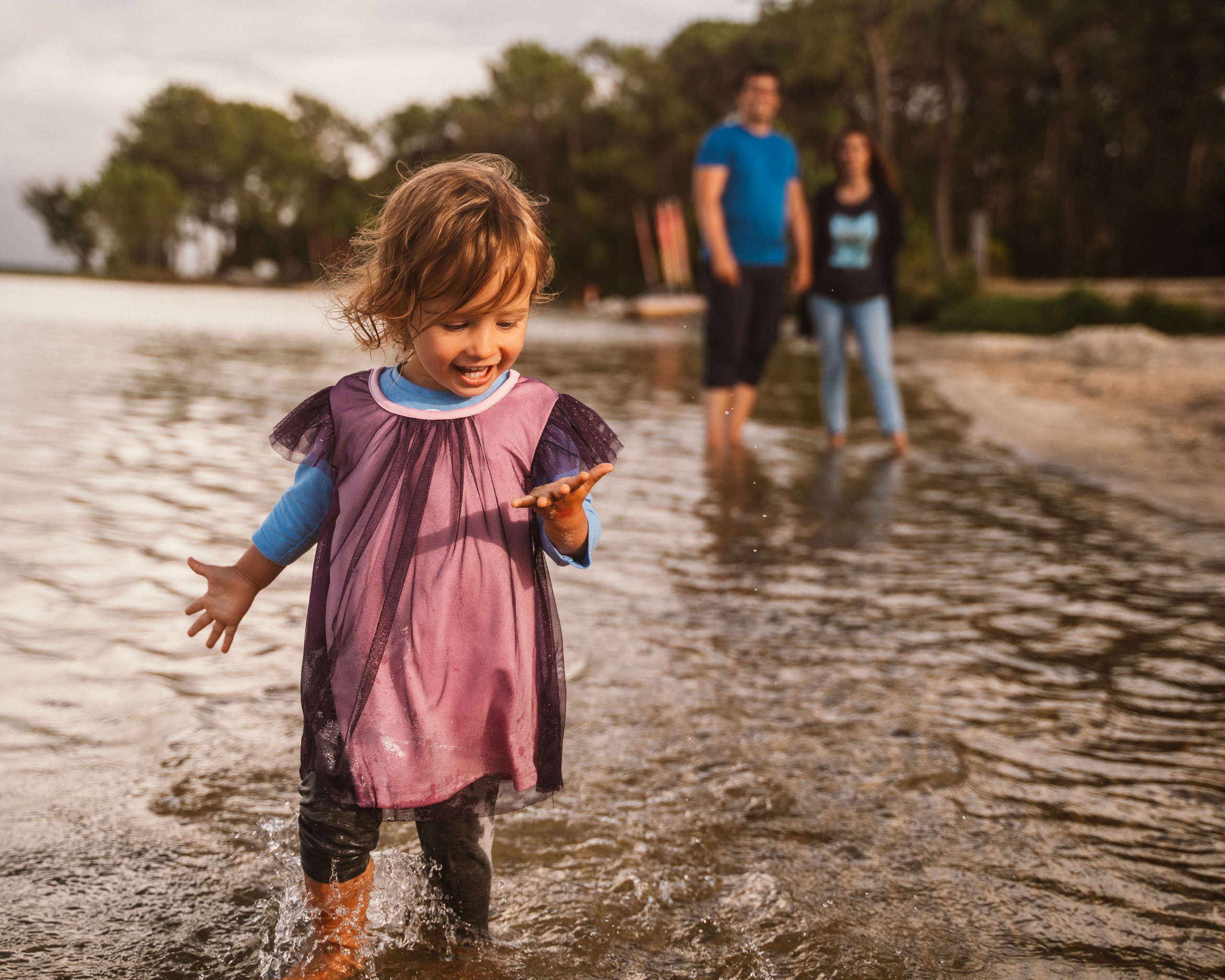 The child and their dad and mom engaged in a fun game of catch amid the picturesque scenery of the lake.