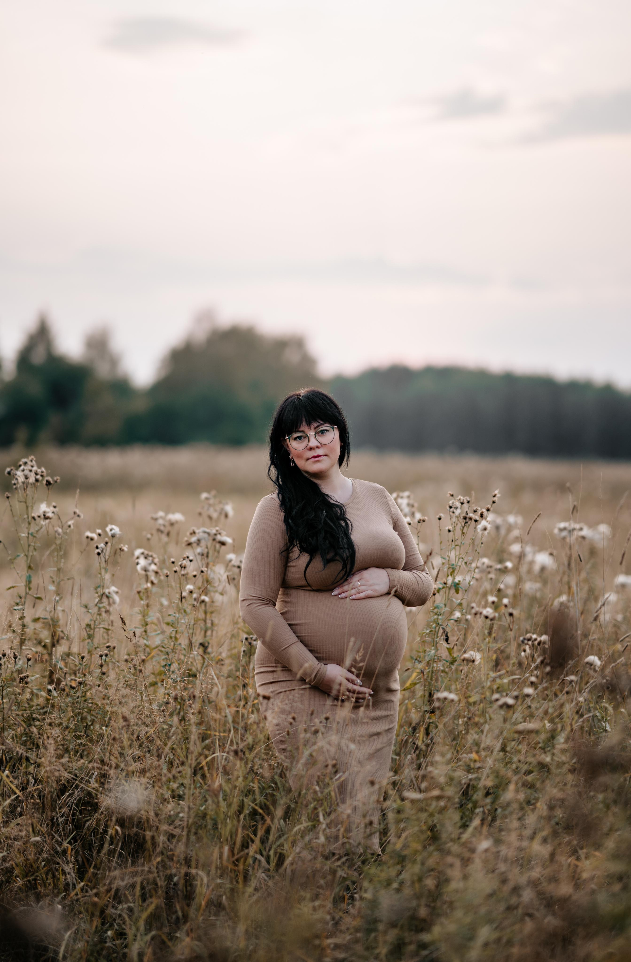 Портрет беременной женщины на закате в полевых цветах.