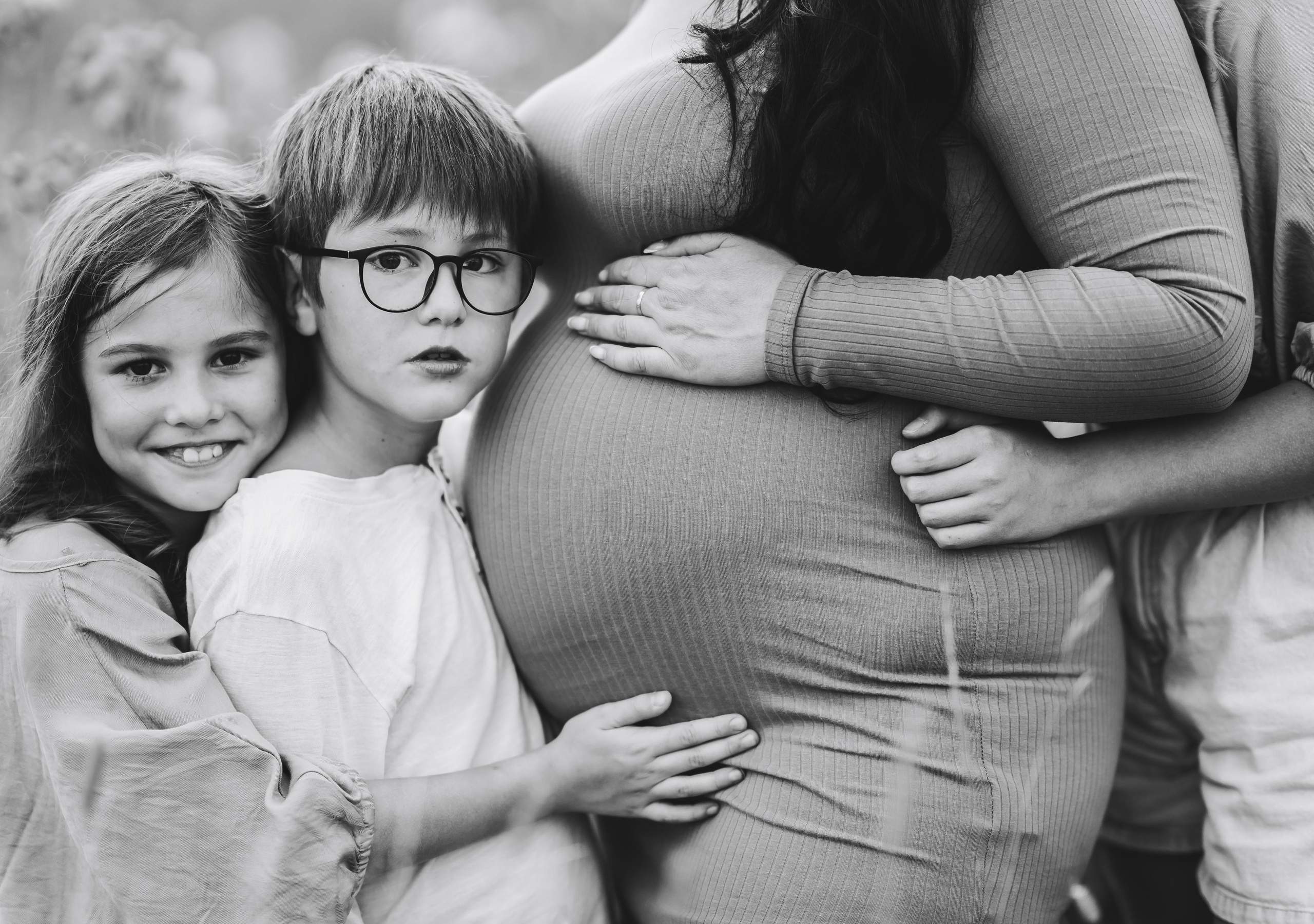 Сын и дочь обнимают маму в ожидании малыша.