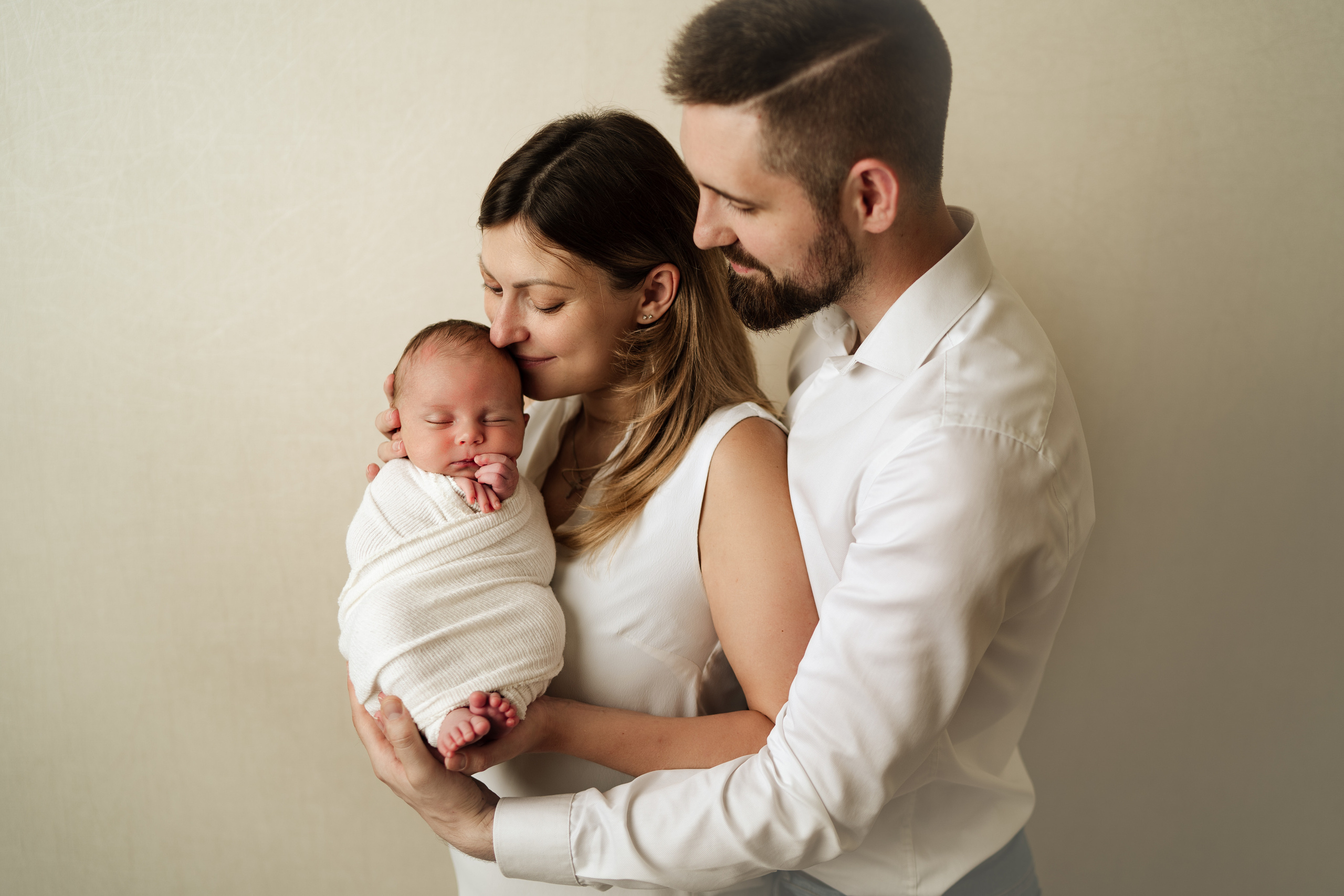 Муж обнимает жену и младенца. Счастливая семья.