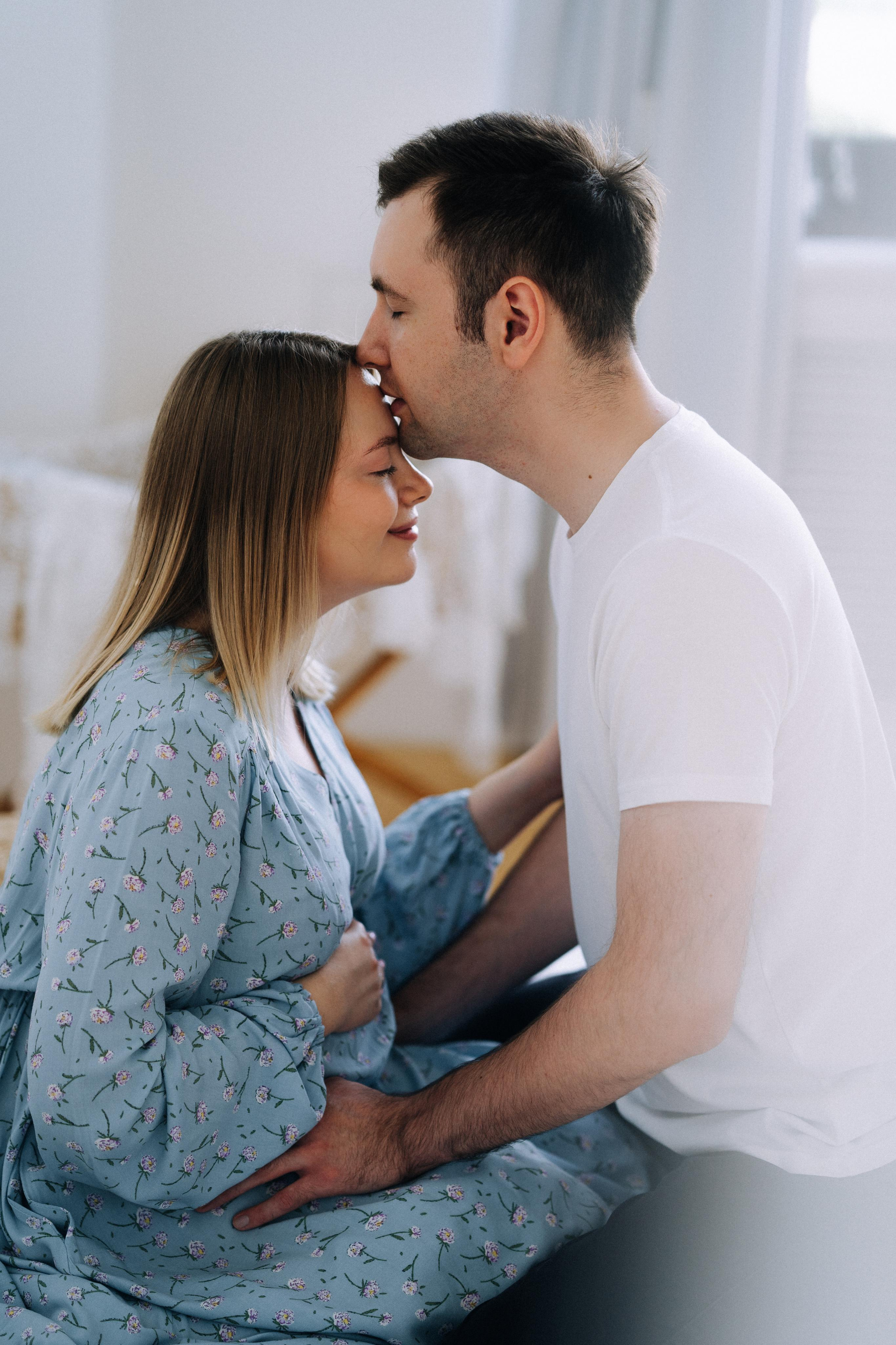 Заботливый муж, нежно целует свою беременную жену.