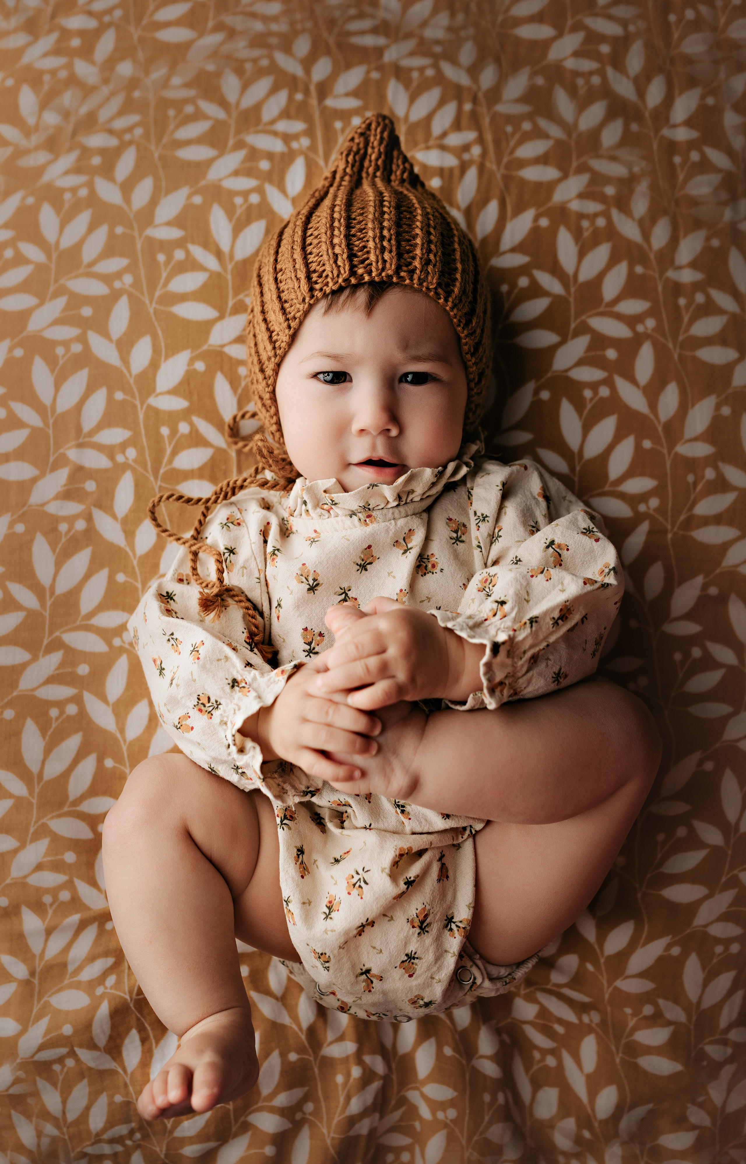 Ребенок держит себя за ножку и смотрит в камеру. Милый кадр.