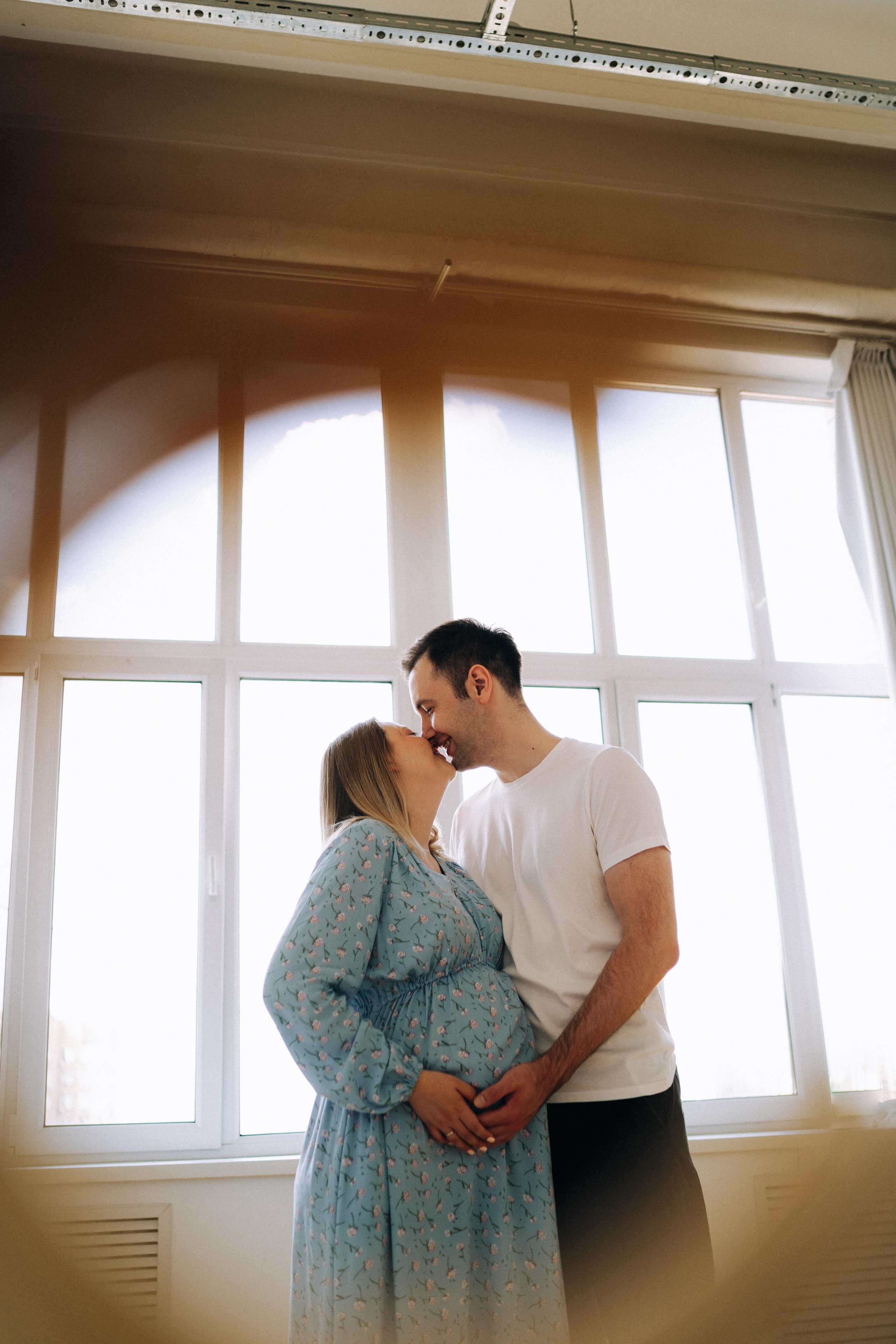 Креативное фото беременности. Пара целуется.