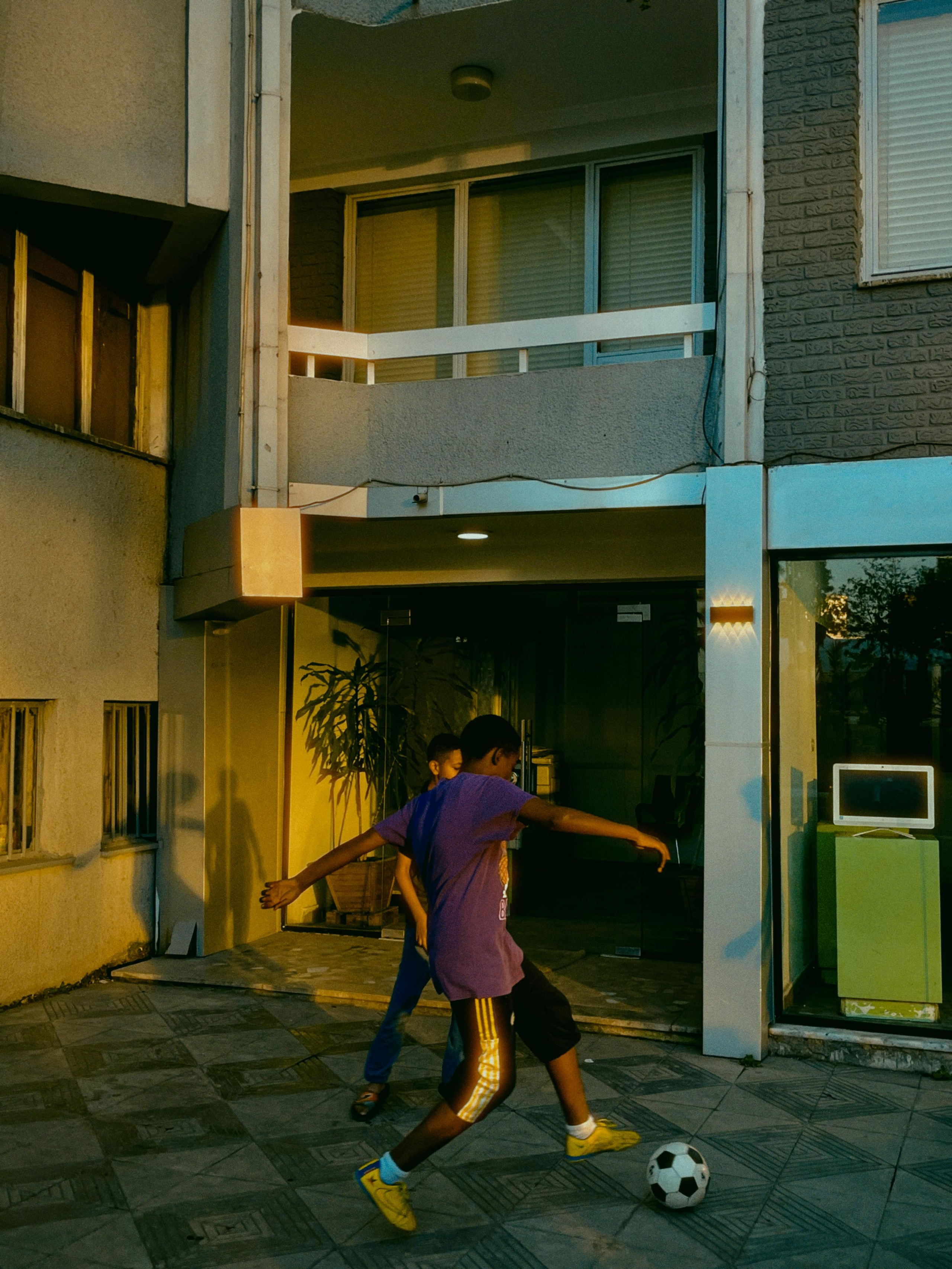 Африканские дети играют в футбол на улице около дома