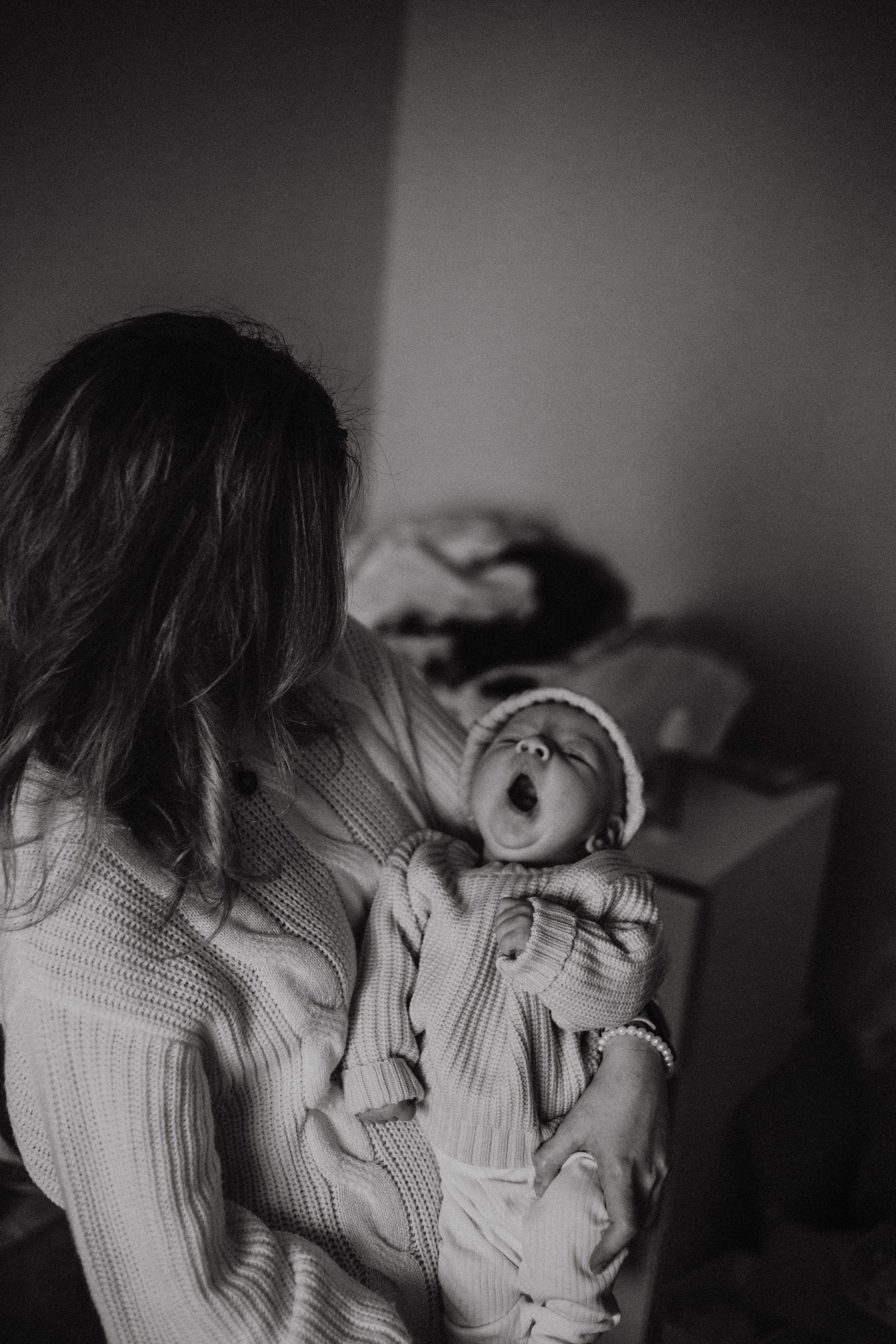 новорожденный малыш зевает на руках у мамы