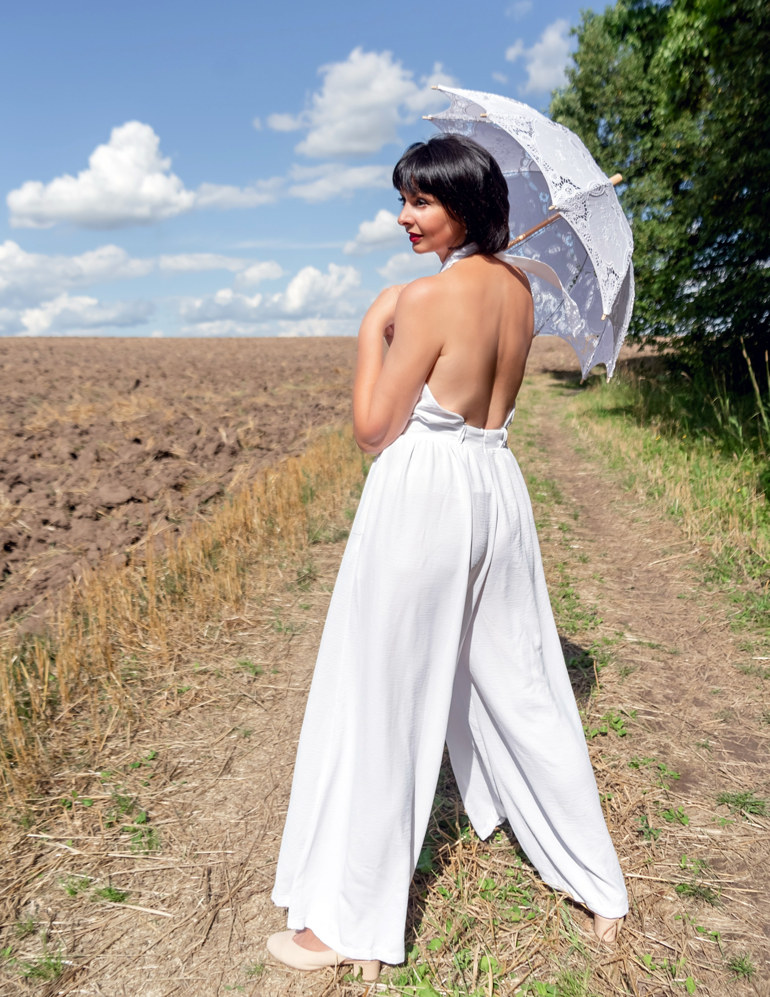 На фото девушка в поле с летним зонтом.