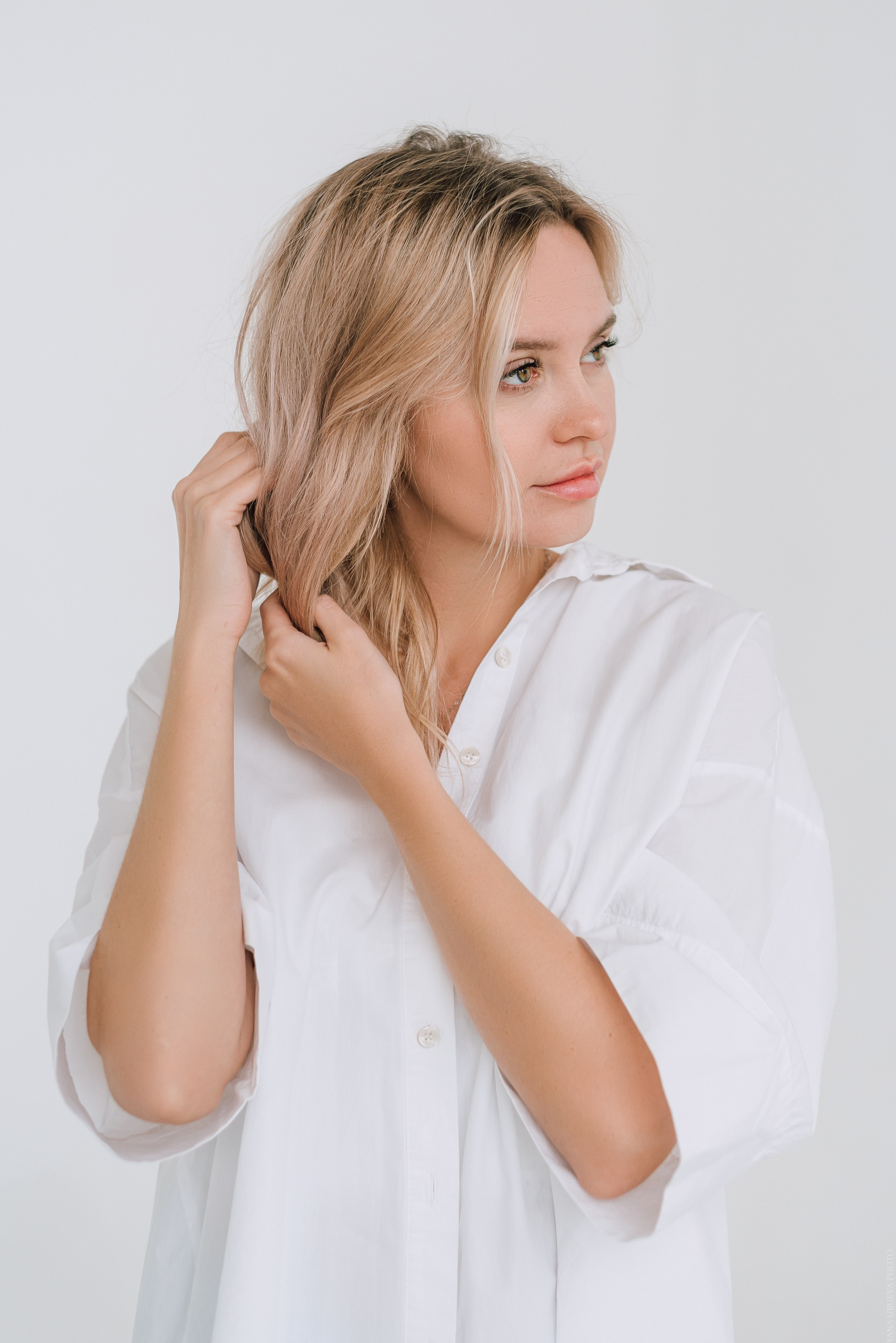Девушка в белой широкой рубашке смотрит в бок