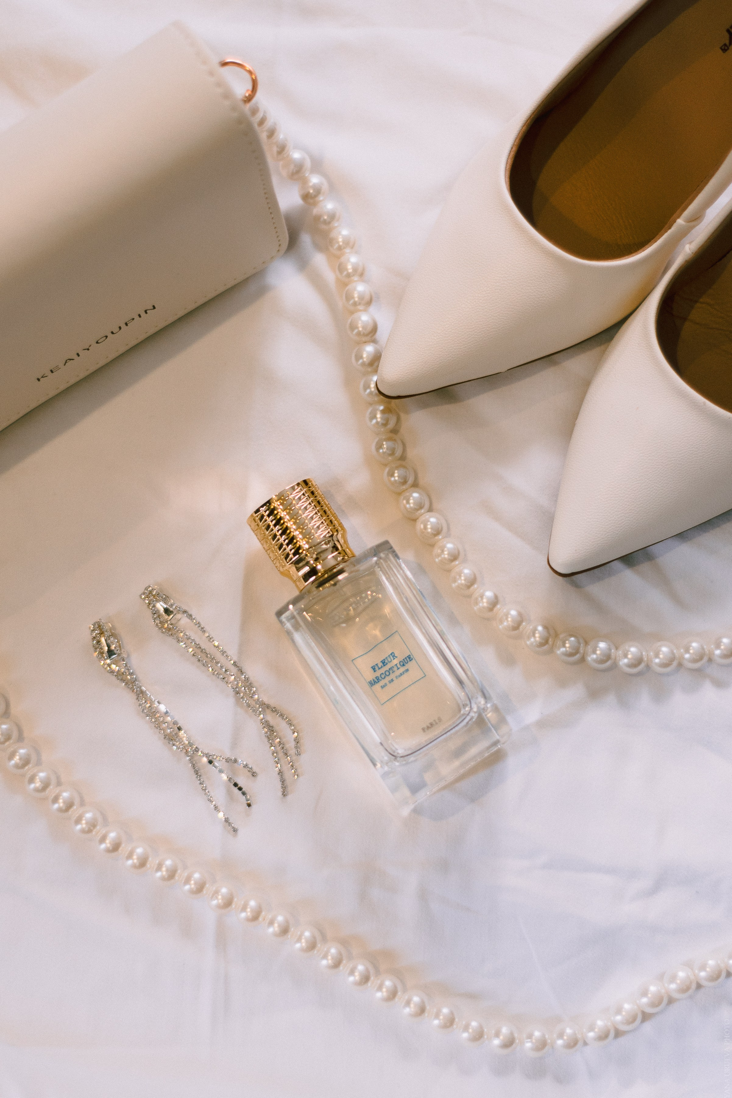 Флакон духов и туфли лежат на кровати