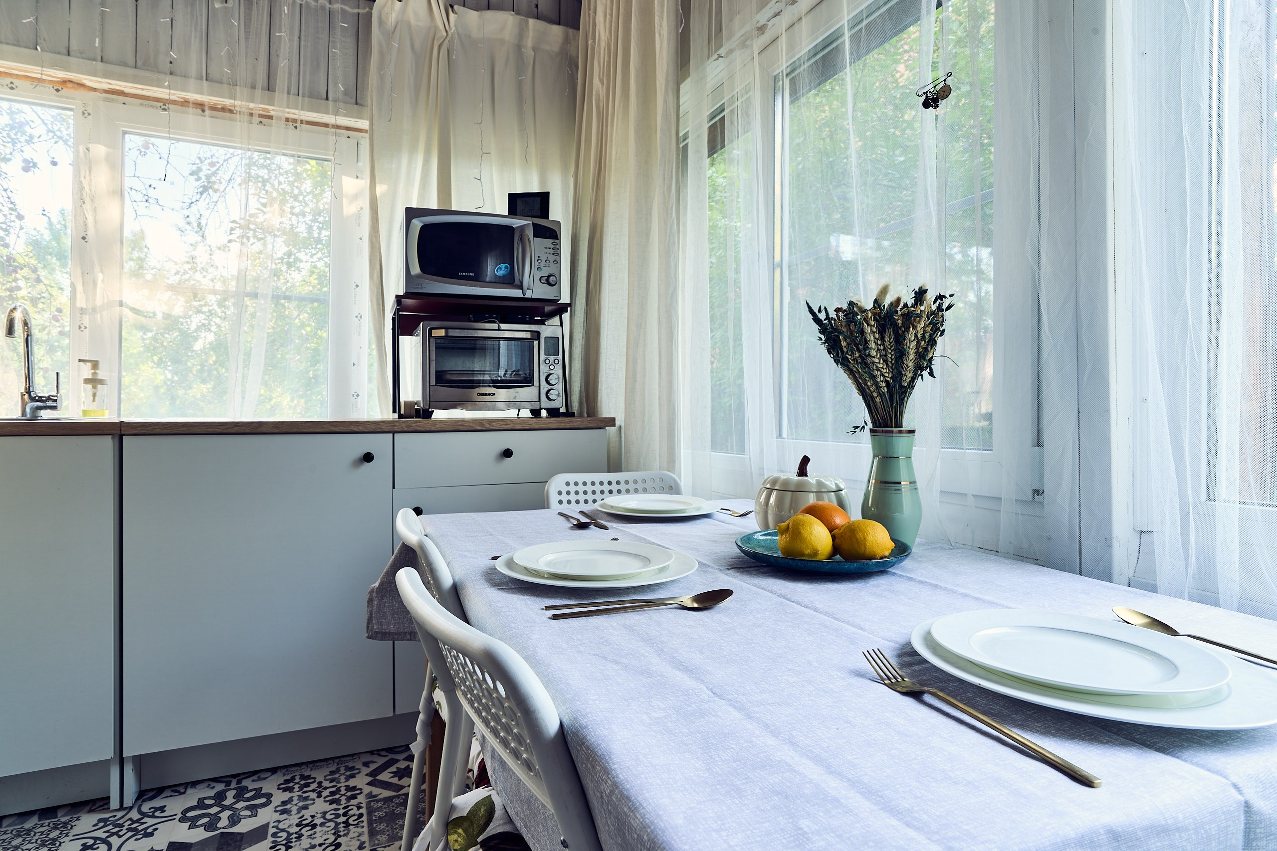 Интерьерная съемка с видом на разделочные стол, печи, раковину и обеденный стол на кухне загородного дома