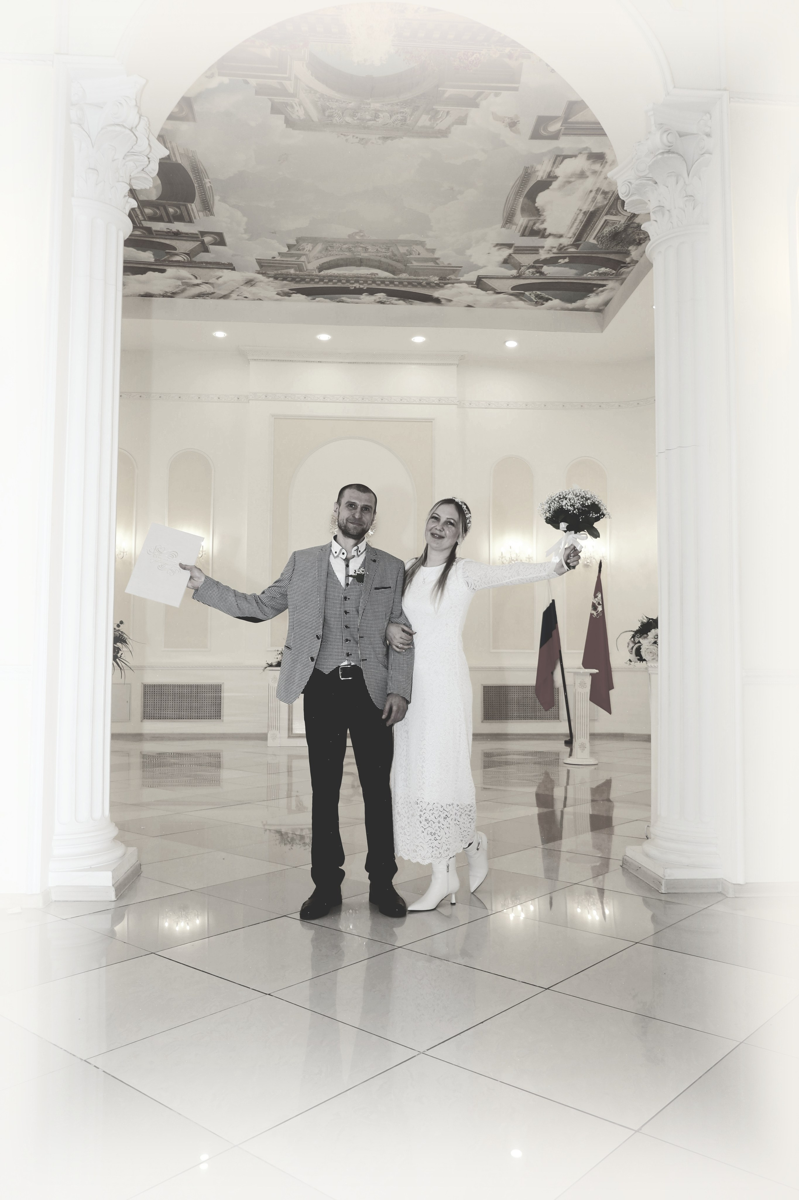 Молодожены в белом парадном зале с колоннами и аркой. Жених держит свидетельство, невеста — букет. Свадебный фотограф Королёв, Московская область, Москва, Юлия Егорова